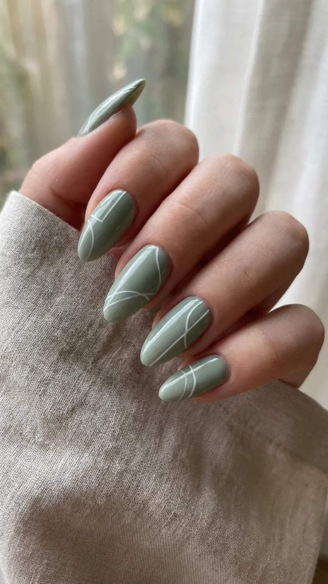sage green almond March nails with glossy finish