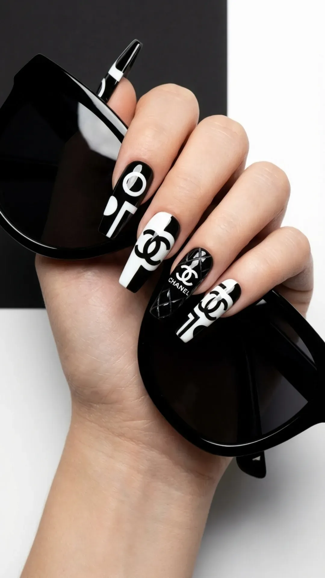 High-contrast luxury nails with branded monochrome designs, featuring iconic logos for a bold statement in fashion.