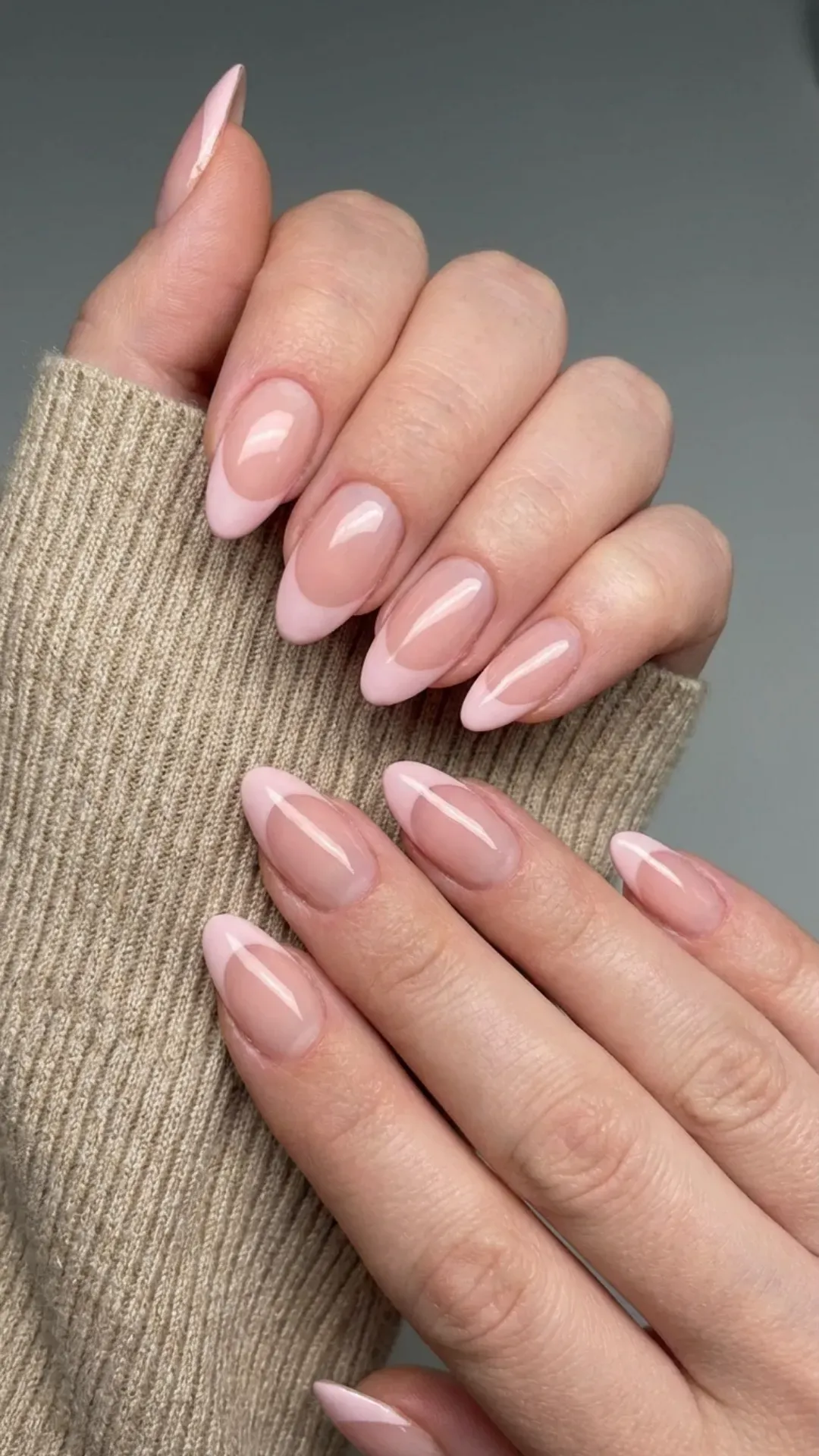 Delicate almond French tip nails in soft blush tones with a natural, glossy finish for a subtle and elegant look.