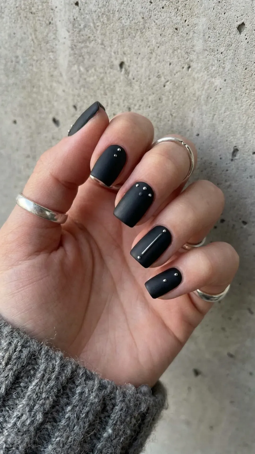 Matte black short nails featuring delicate silver studs for a subtle yet edgy look, perfect for a modern and sophisticated style.