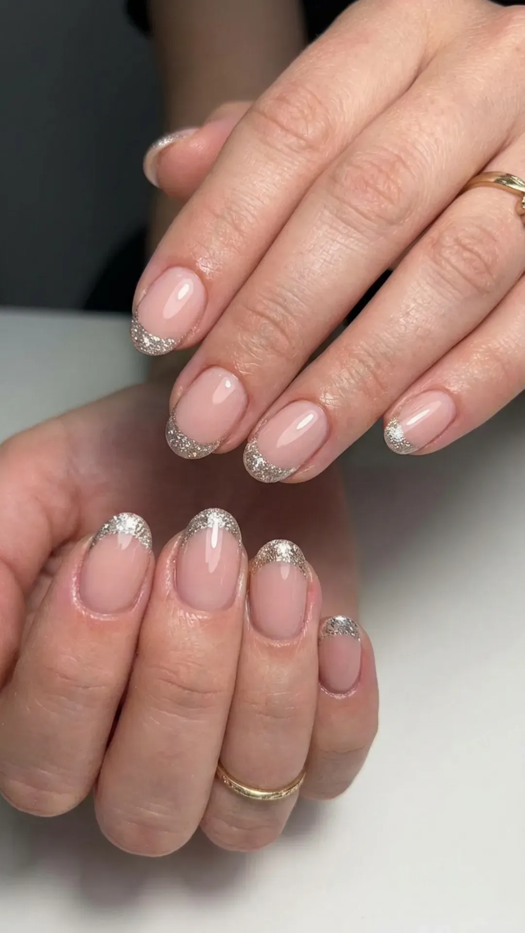 Elegant short nails with sparkling glitter on French tips, accentuating the nude-pink base for a glamorous look.