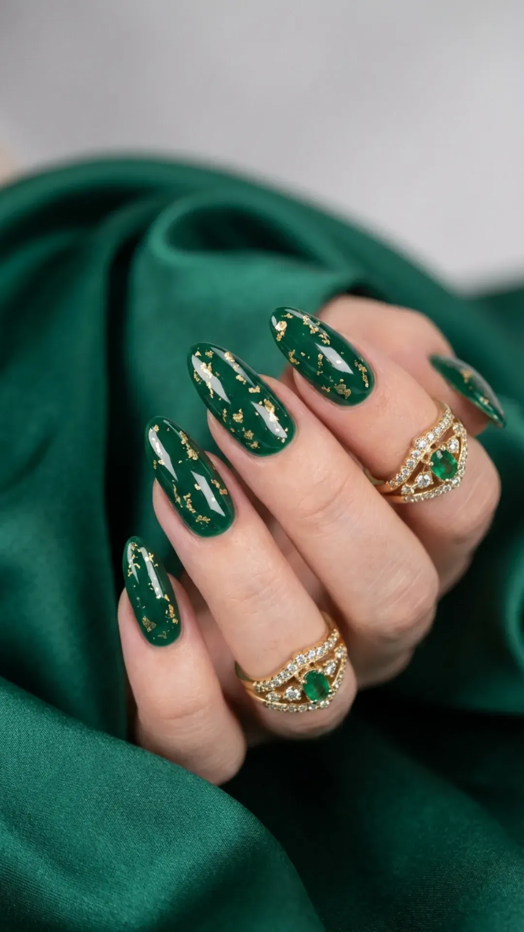 Long almond emerald green prom nails with gold foil accents, glossy luxury manicure close‑up