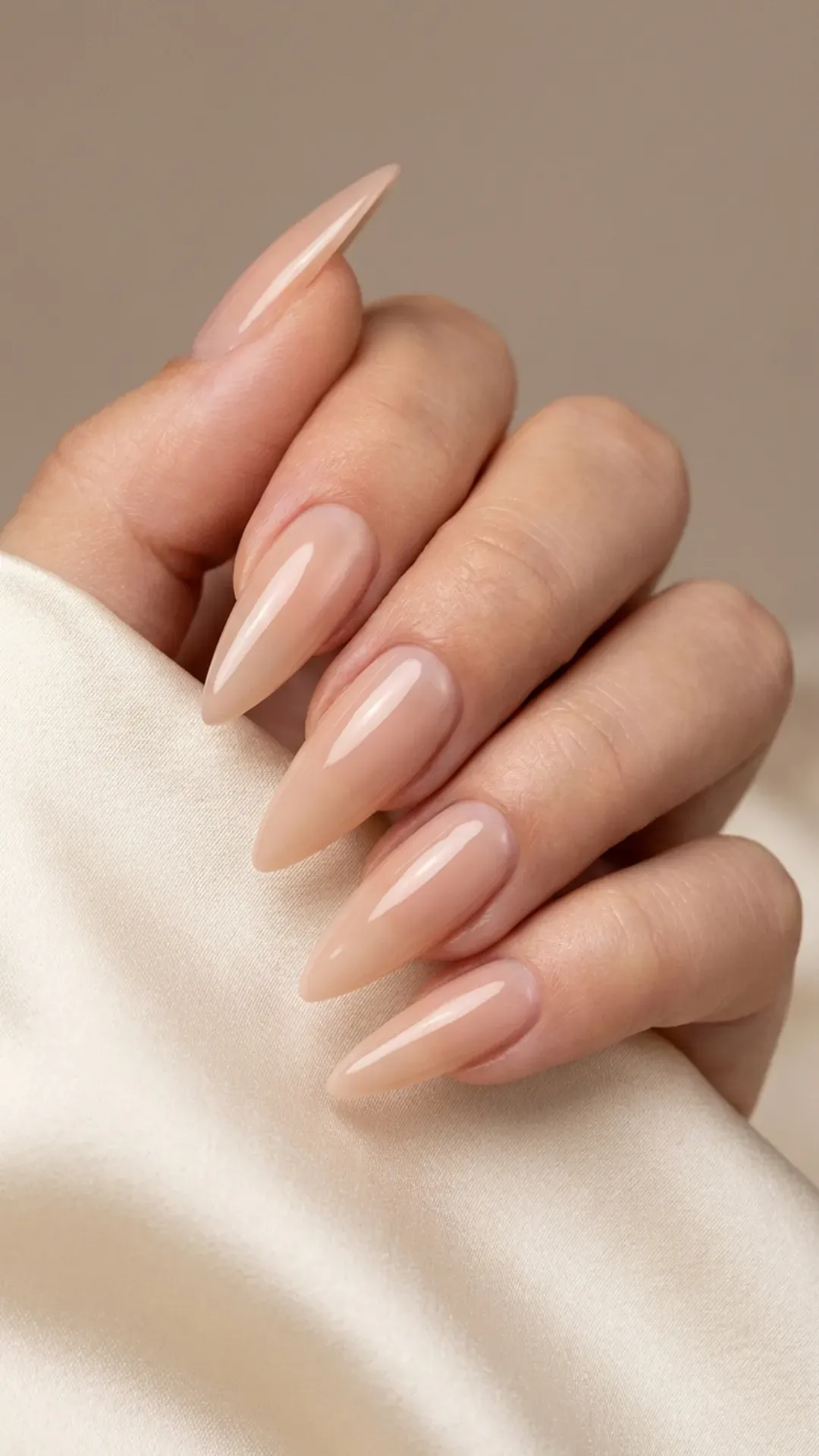Glossy nude stiletto nails with sharp tapered tips and clean cuticles