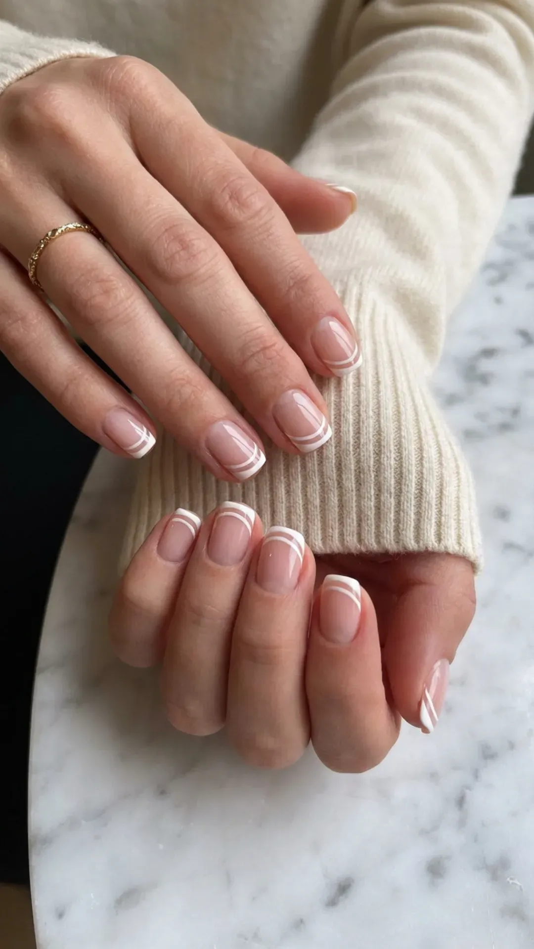 Sophisticated short nails adorned with white striped French tips, offering a crisp contrast to the natural nail color for a refined look.