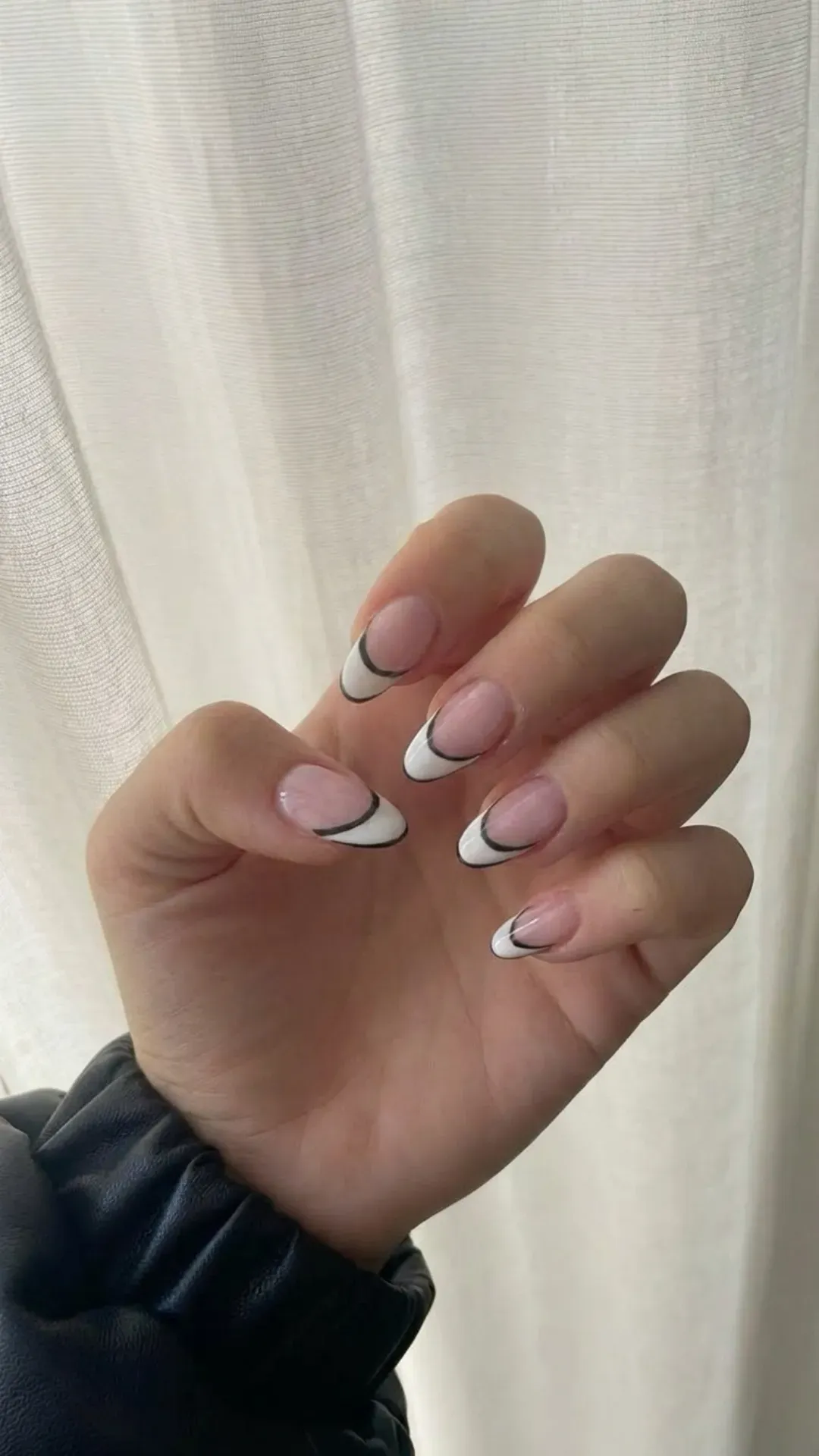 Stylish almond French tip nails featuring a white base with a striking black outline for a contemporary contrast.