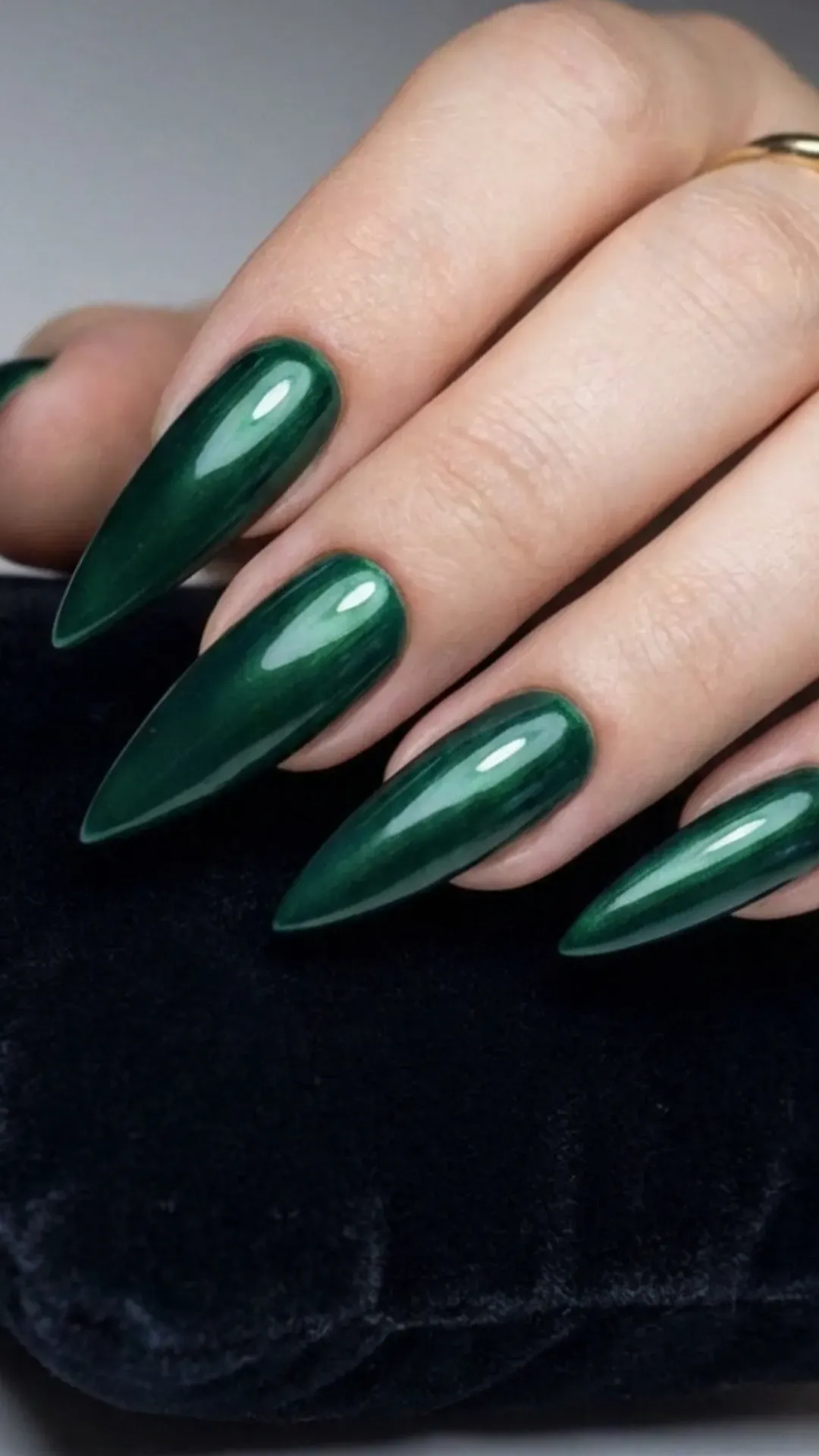 Emerald green stiletto nails with a glossy jewel-tone finish