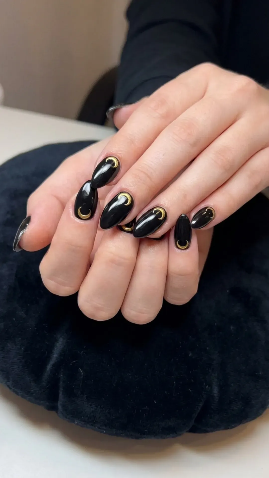 Elegant black nails adorned with a striking gold crescent moon design at the nail base, showcasing a perfect blend of boldness and sophistication for a chic, celestial-inspired look.