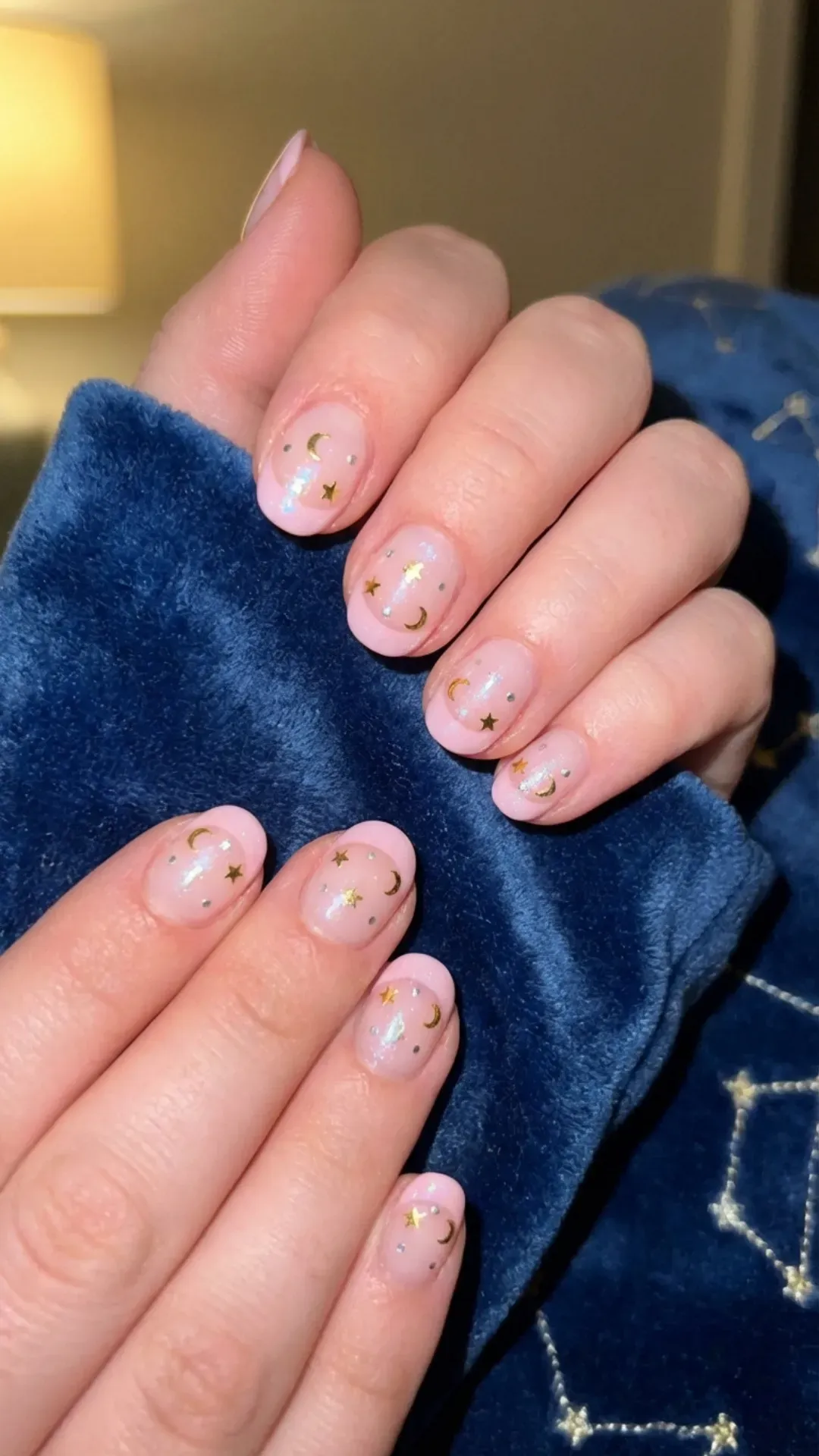 Short nails with a celestial theme, showcasing delicate star designs on a pale pink French tip, evoking a dreamy starry night sky.