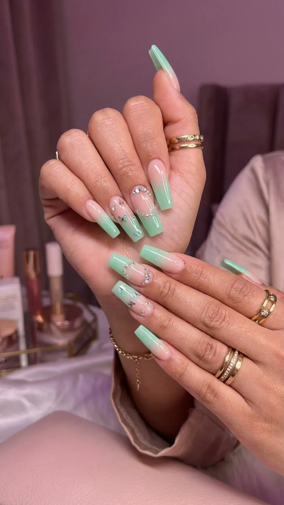 Mint green ombre coffin nails with rhinestone accents on nude base