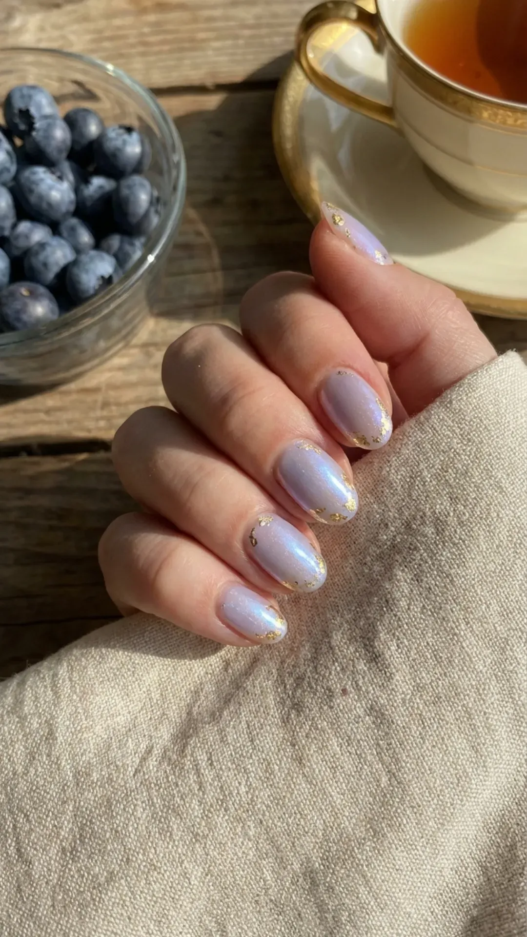 Shimmering blueberry milk nails with gold foil accents that give a rich and luxurious look to a classic summer style