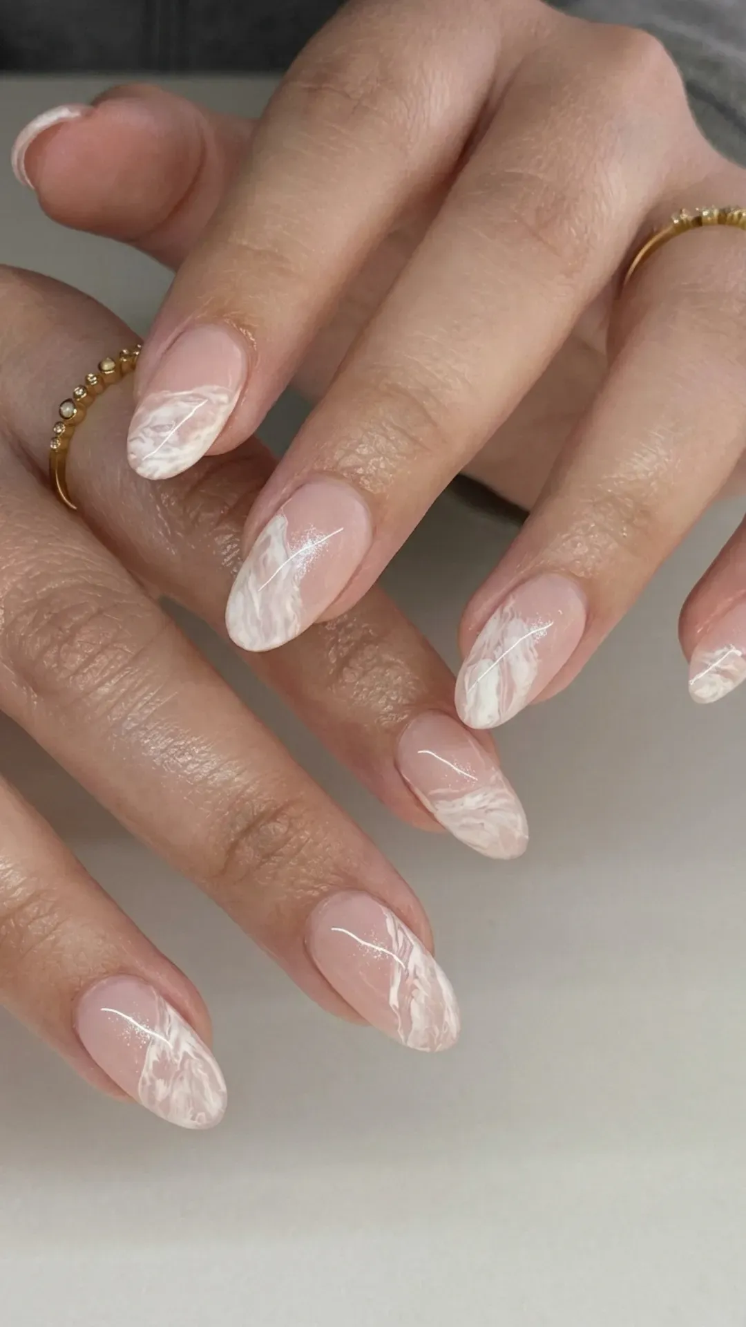 Elegant almond French tip nails with a white marble effect, offering a sophisticated and unique twist on nail art.