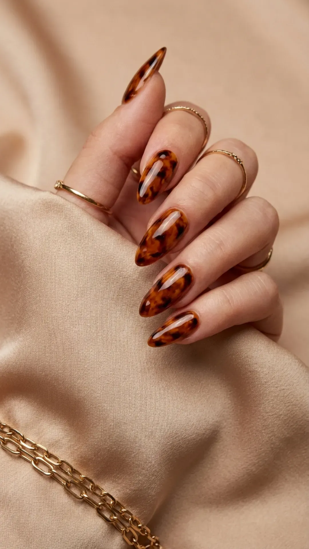 Sleek almond-shaped nails with a luxurious tortoiseshell design, showcasing a glossy finish with swirls of black, amber, and brown.