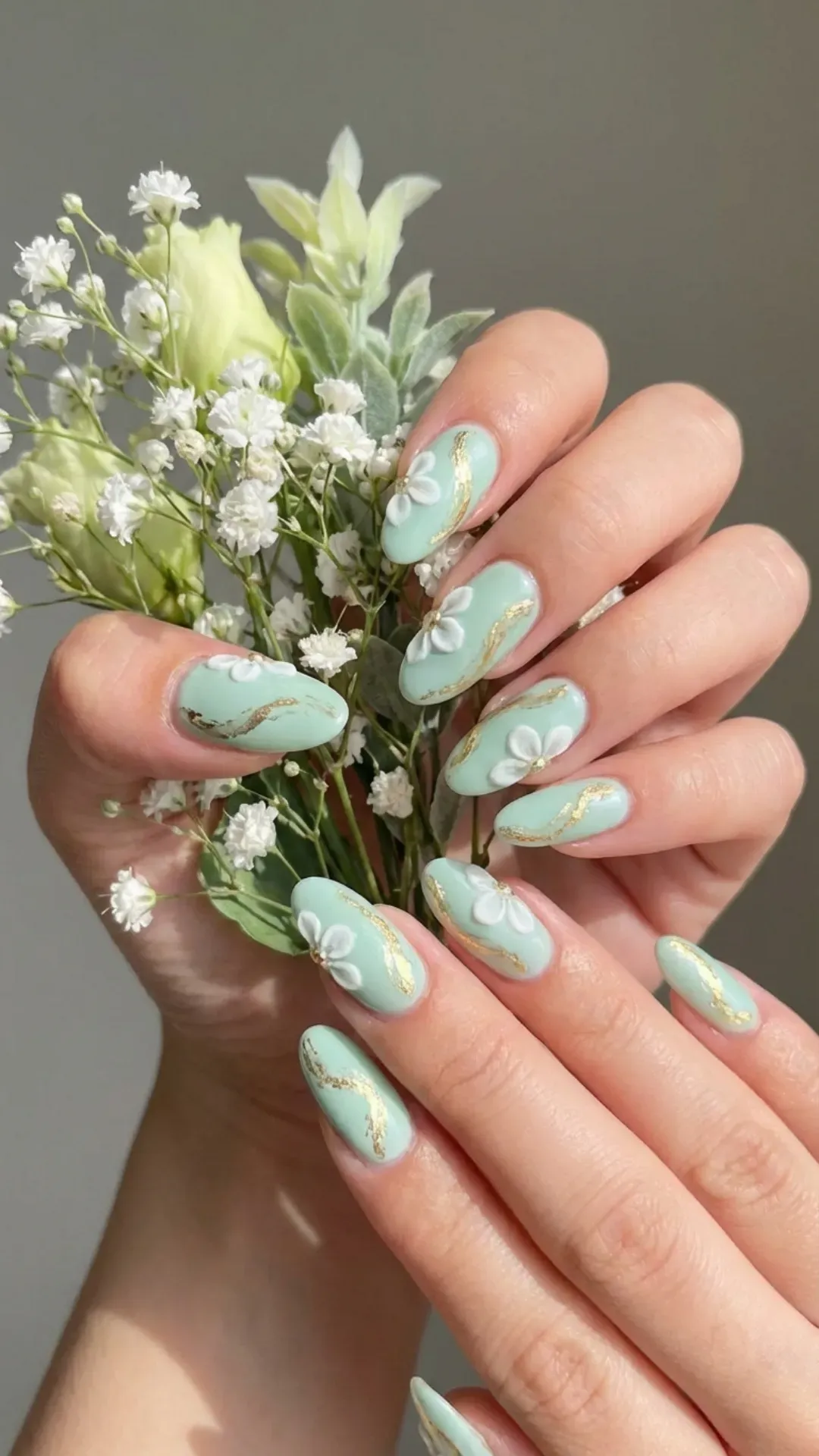 Pastel mint green nails with tiny white floral accents and gold details