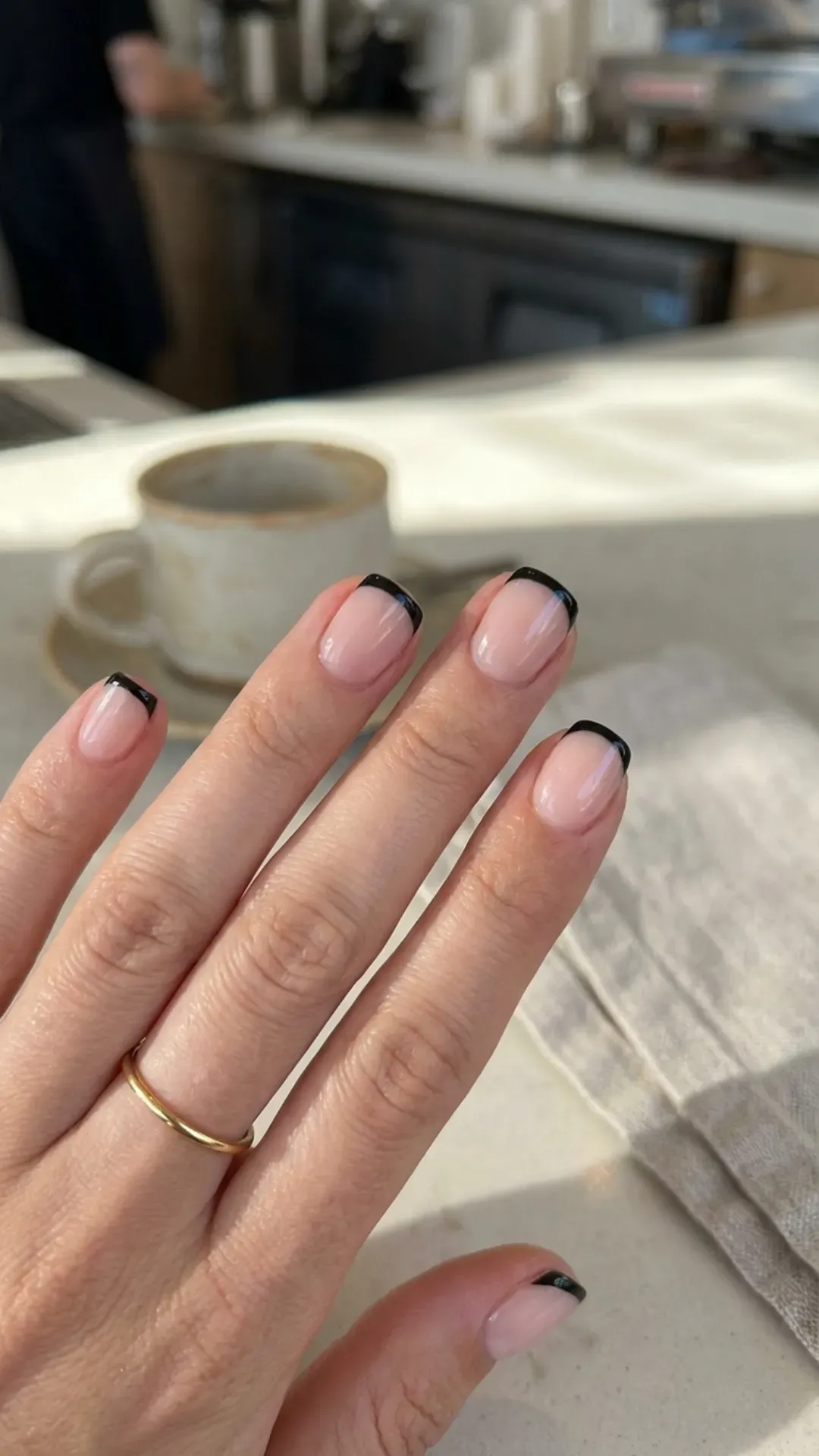 Classic French manicure with a twist, showcasing short nails with black tips against a natural nail base, offering an elegant and timeless appeal.
