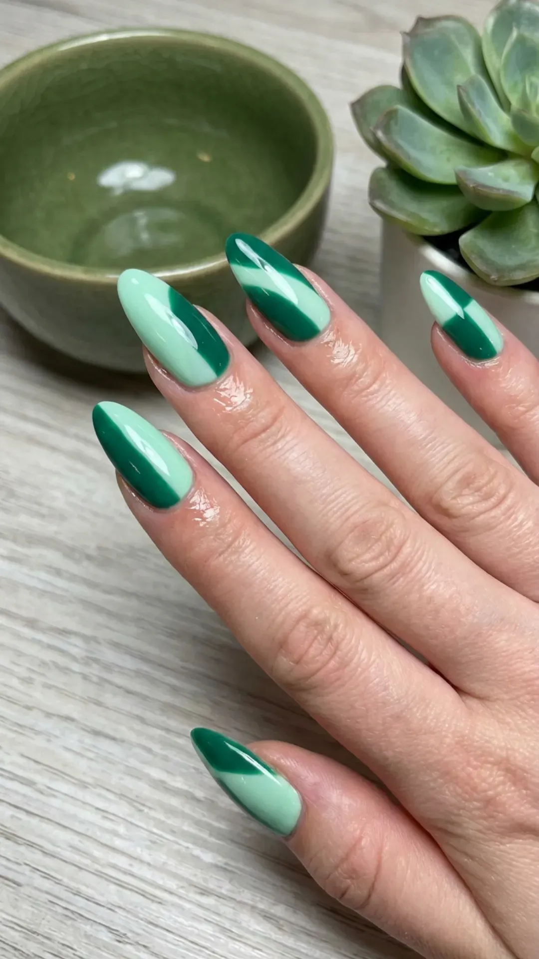 Almond nails with two‑tone mint and deep green diagonal design on glossy finish