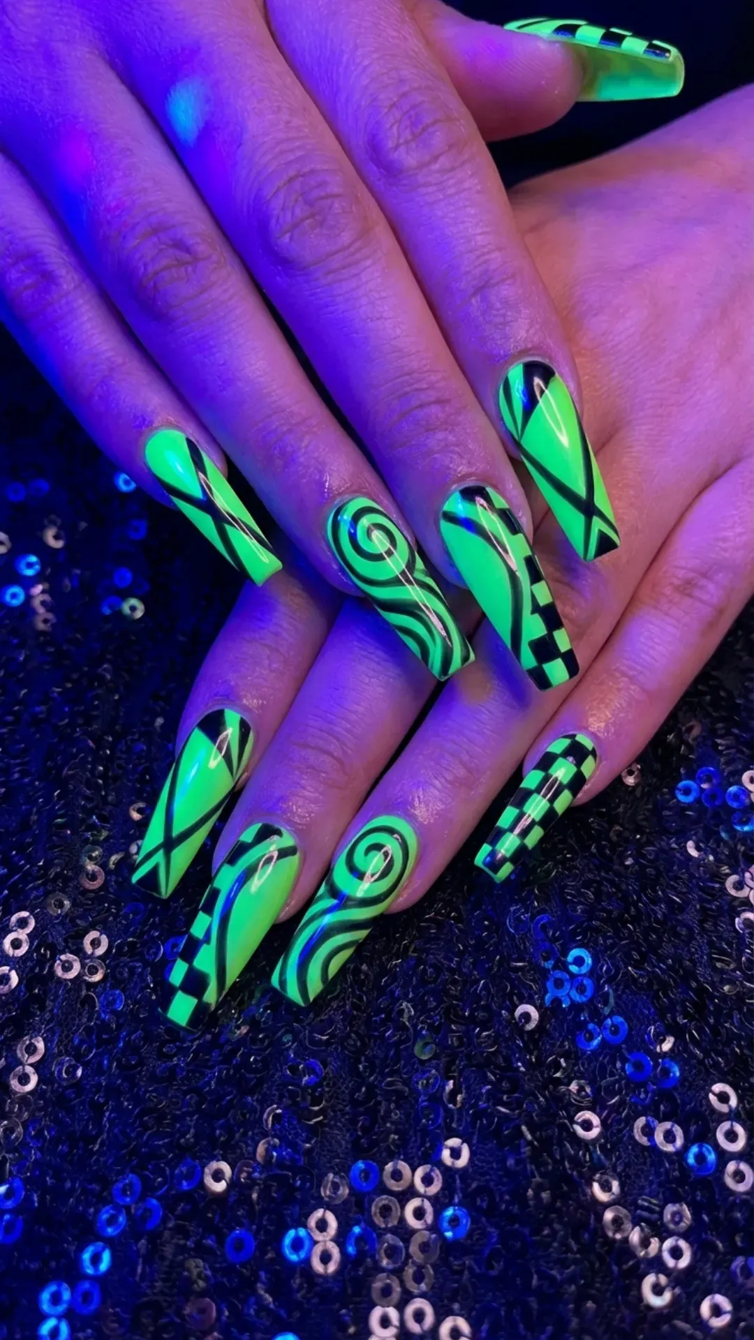 Neon green long coffin nails with black graphic patterns under UV lighting