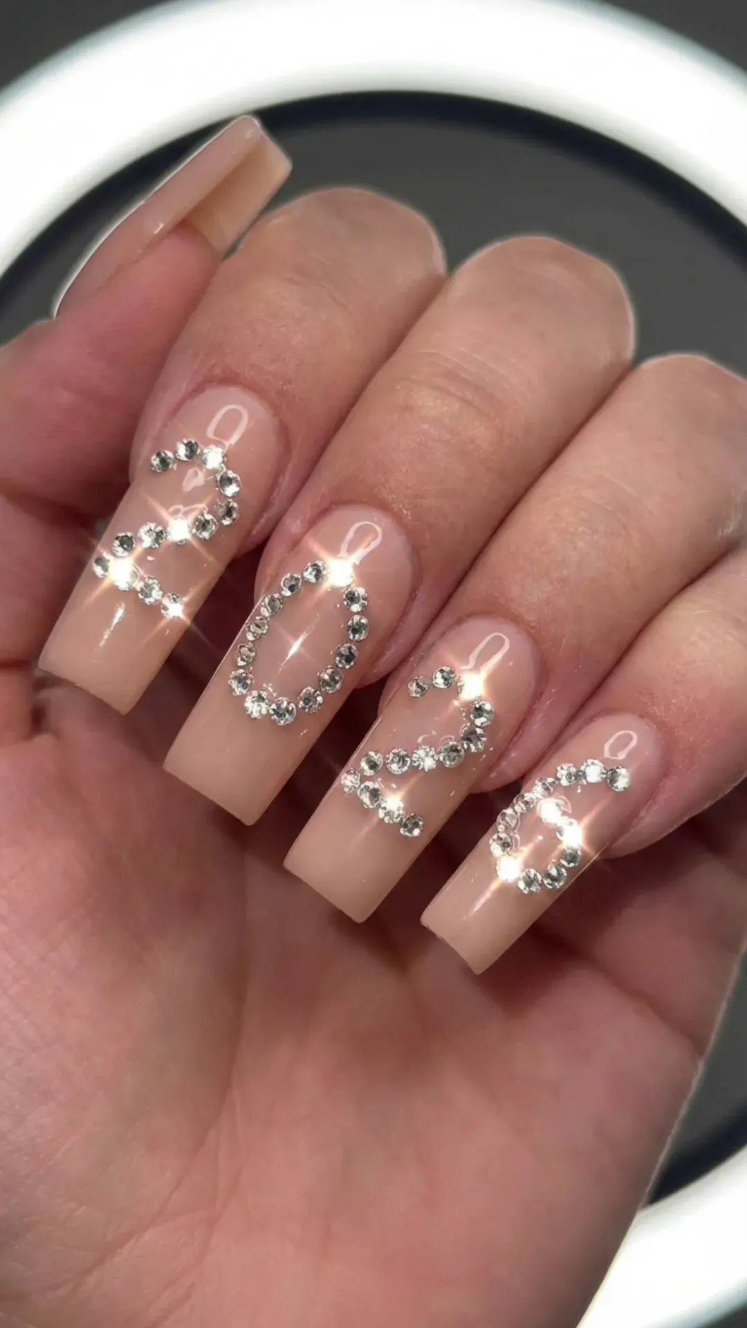long nude acrylic nails with 2026 spelled in crystal rhinestones by VANSWEG.COM