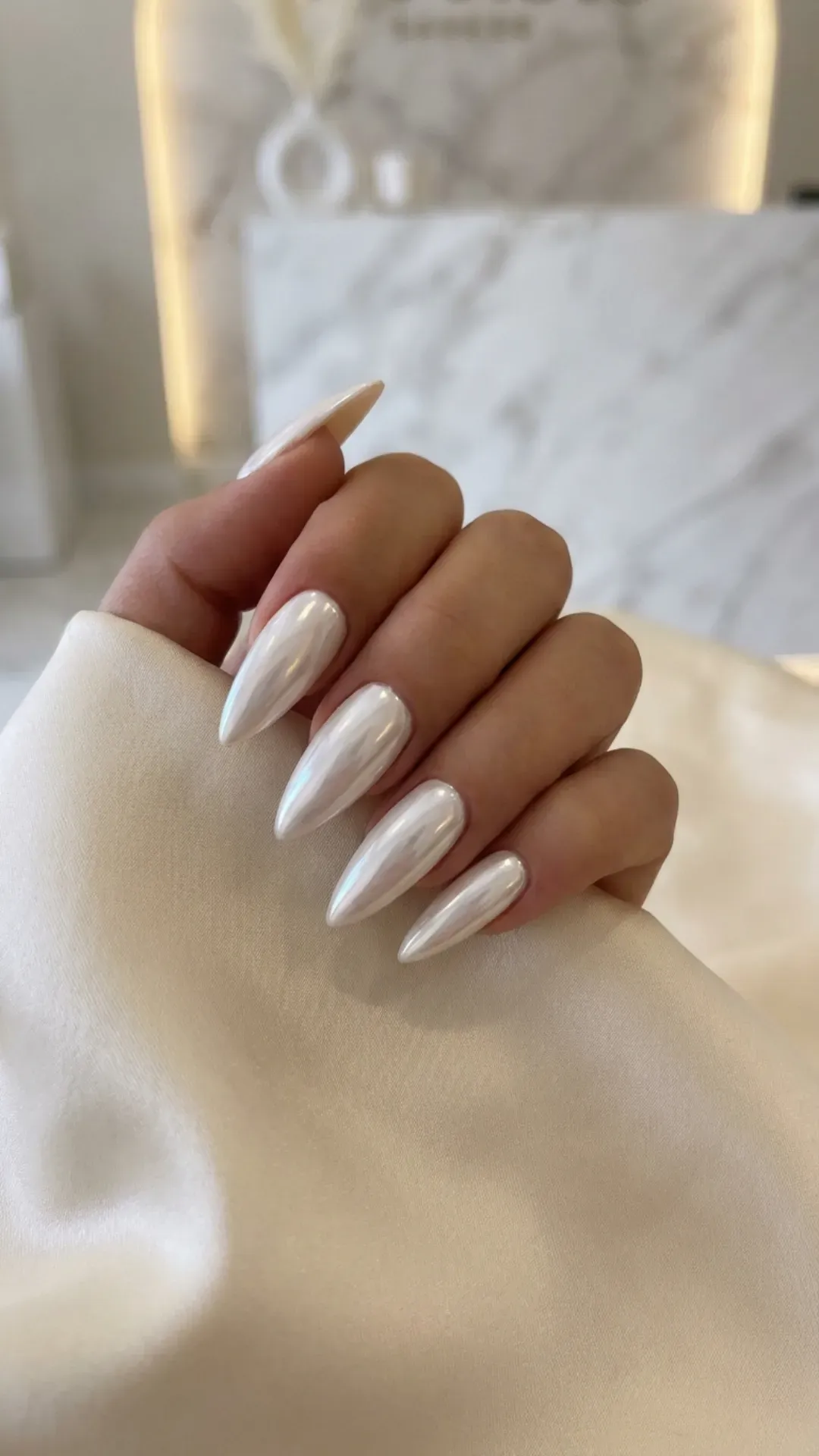 White chrome stiletto nails with a pearly reflective sheen