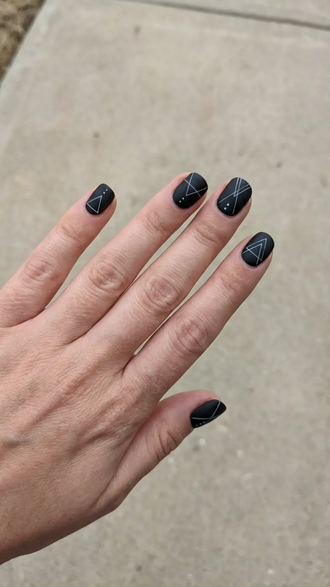 Chic and minimalist short black nails with precise white lines, presenting a modern geometric design that's both stylish and understated.