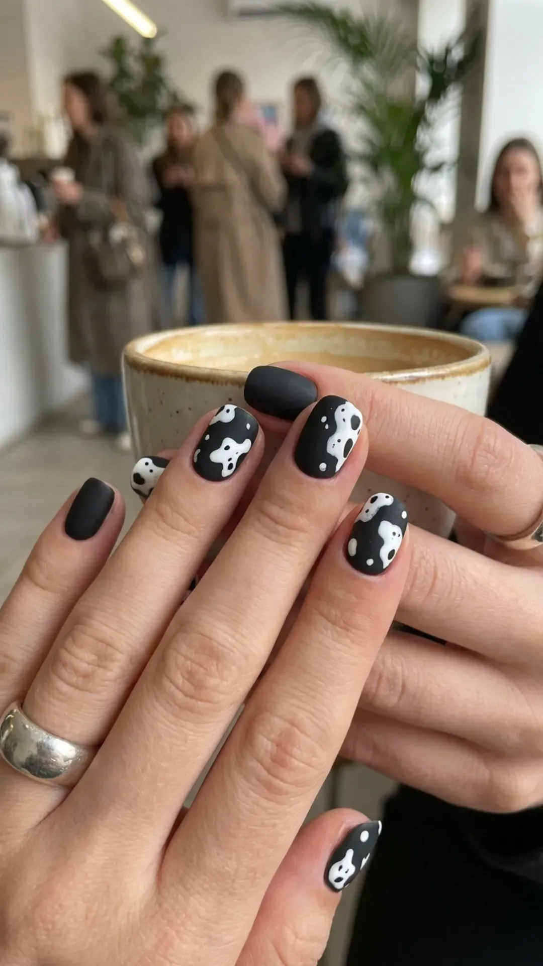 Trendy short black nails with unique white cow print patterns, offering a playful and fashion-forward nail art choice for those looking to stand out.