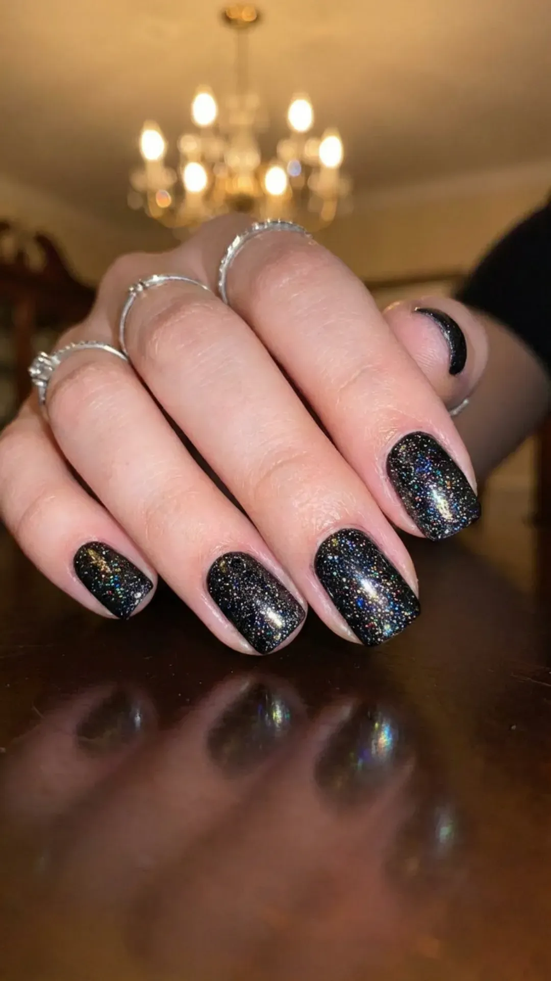 Sparkling short black nails with a glitter overlay, creating a glamorous and eye-catching look that shimmers beautifully under the light.