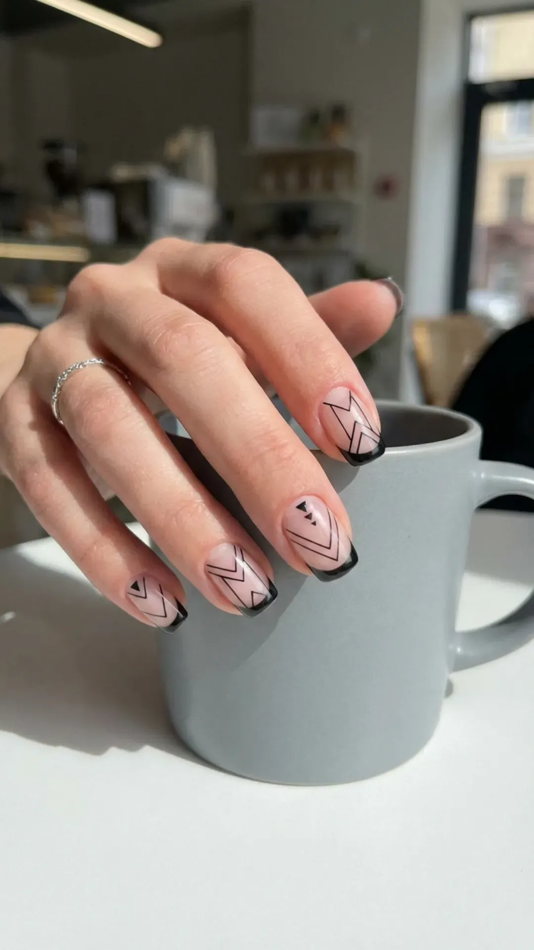 Modern short French tip nailswith geometric black lines over a transparent base, creating an edgy yet sophisticated nail art design.