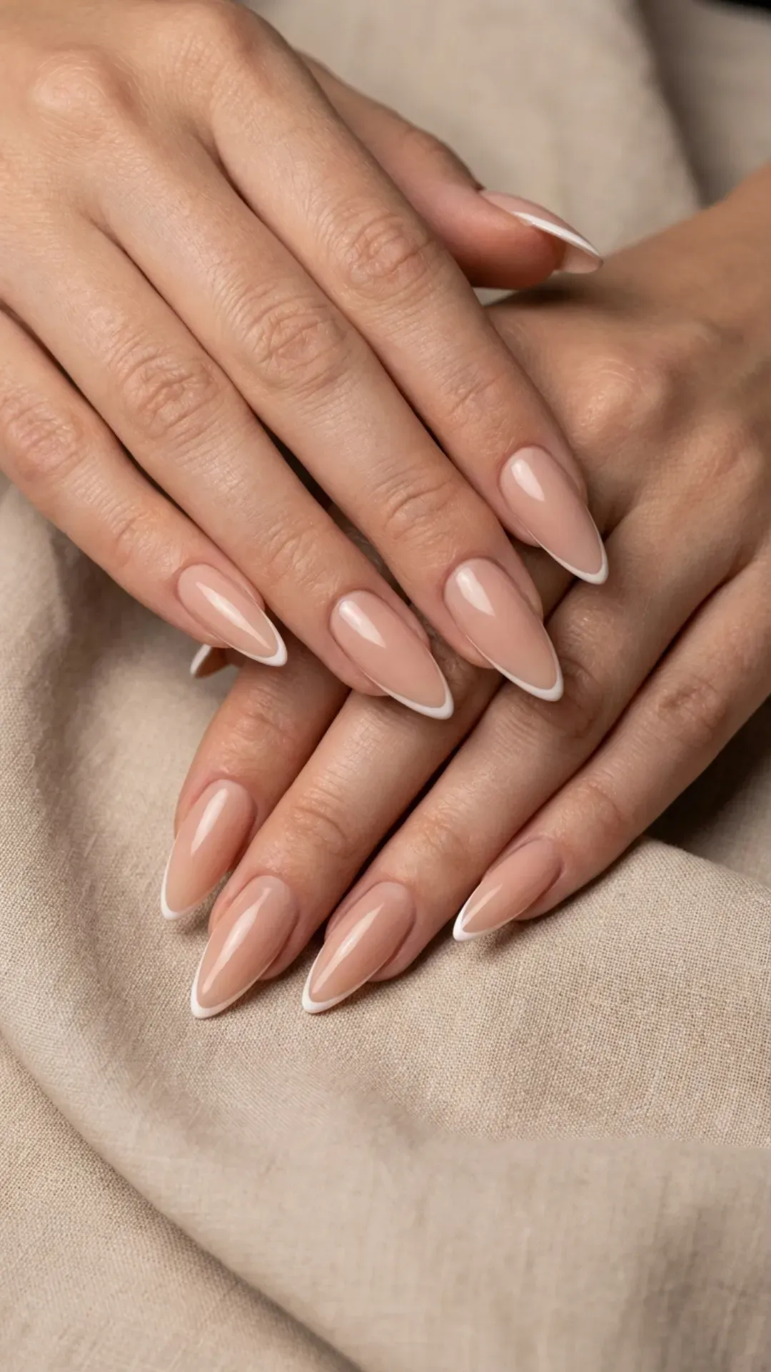 Nude stiletto nails with thin French tips and glossy finish
