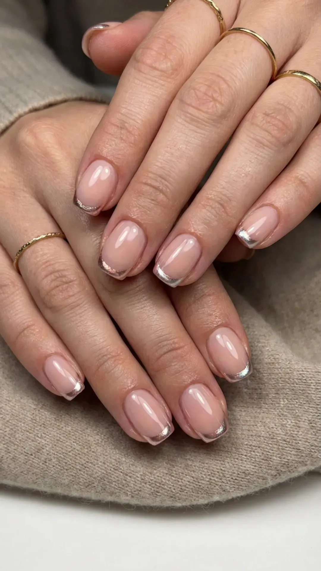 Chic short nails with metallic French tips that shimmer against a soft nude-pink base, perfect for adding a touch of elegance to any look