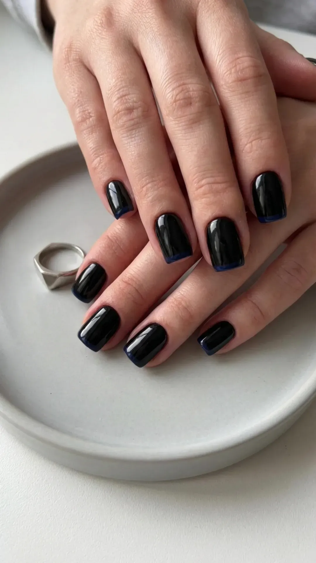 Short black nails with a modern flair, featuring dark navy tips for a subtle color contrast, ideal for a chic and contemporary nail design.
