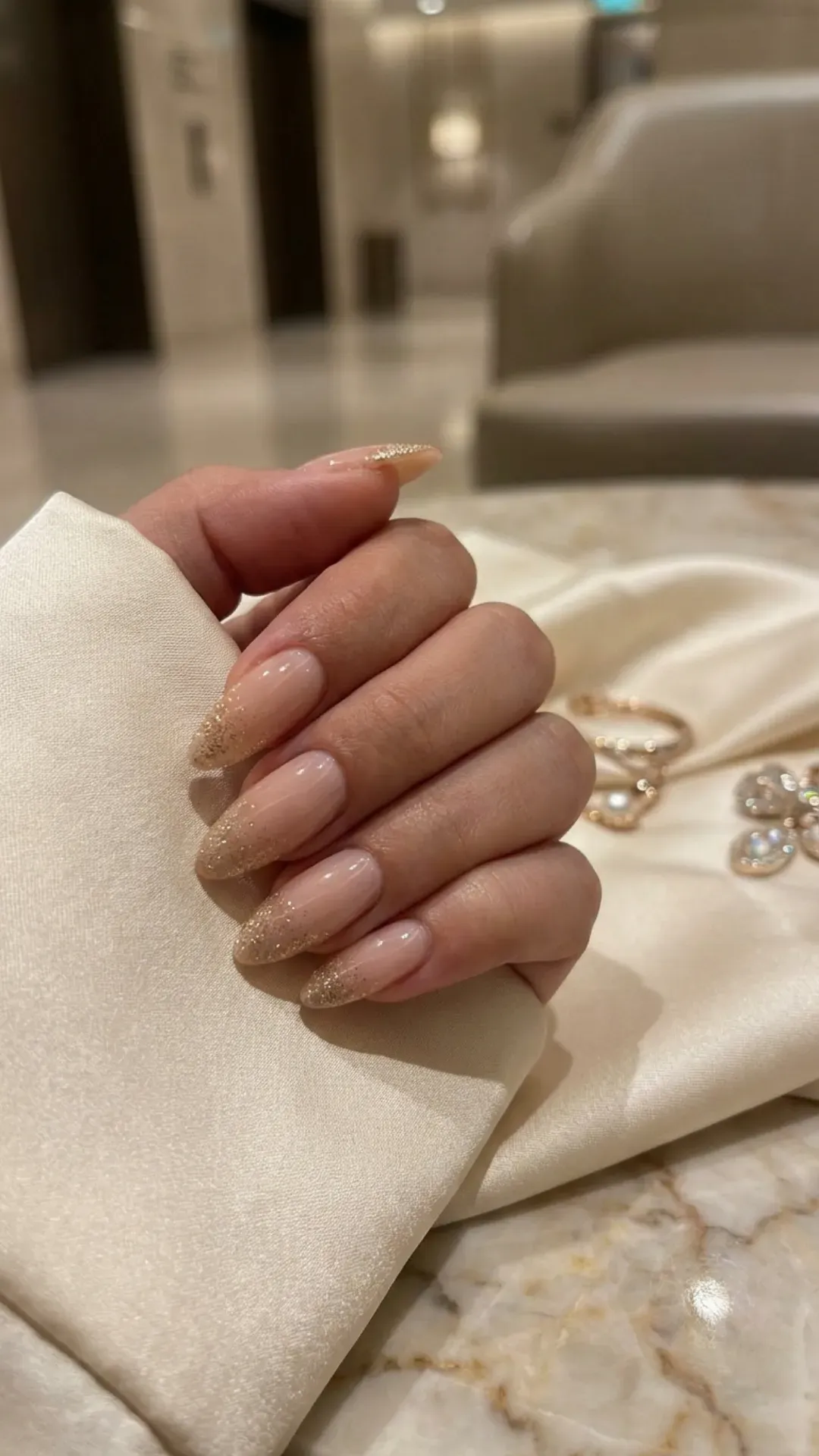 Nude glossy prom nails with gold shimmer accents, elegant neutral manicure