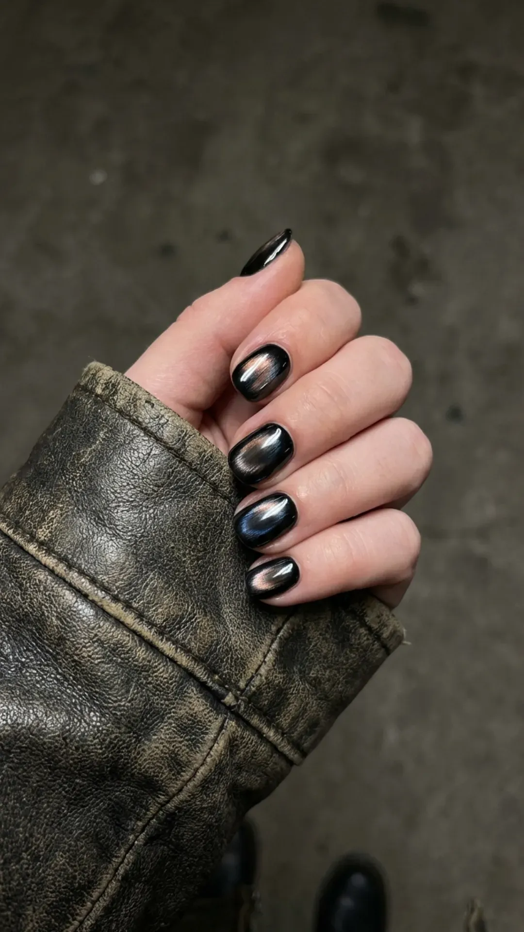 Short black nails with captivating metallic undertones that catch the light and add a touch of industrial chic to any look.