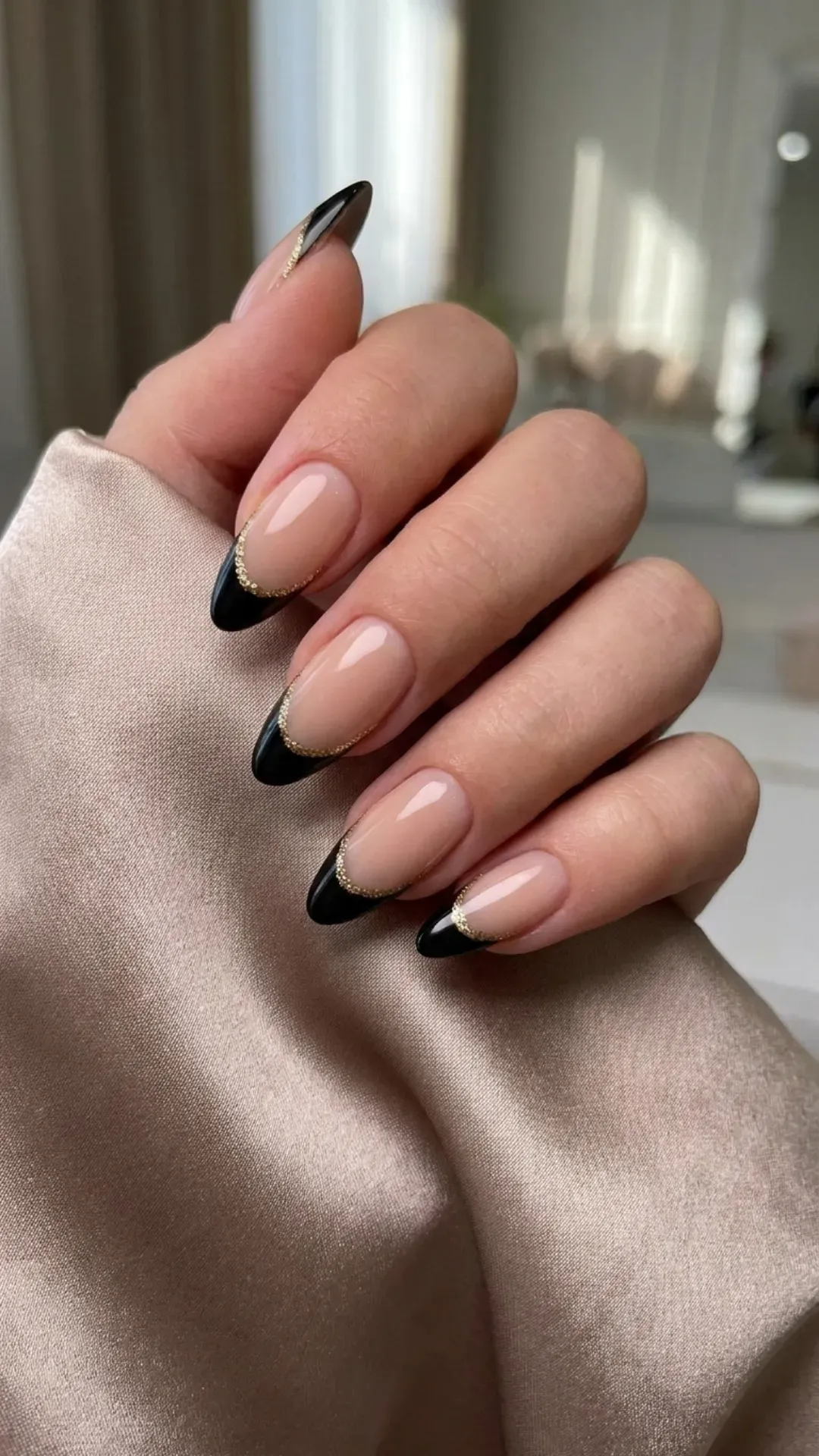 Elegant French manicure with nude base, black tips, and a shimmering gold glitter line for a classy finish