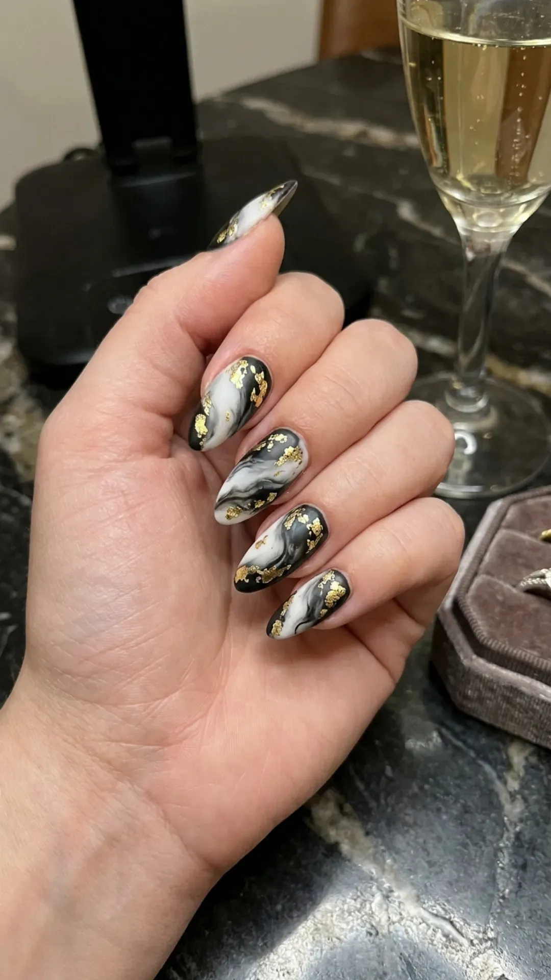 Dramatic black and white marble nails with bold gold foil accents, offering a luxurious and edgy nail design.
