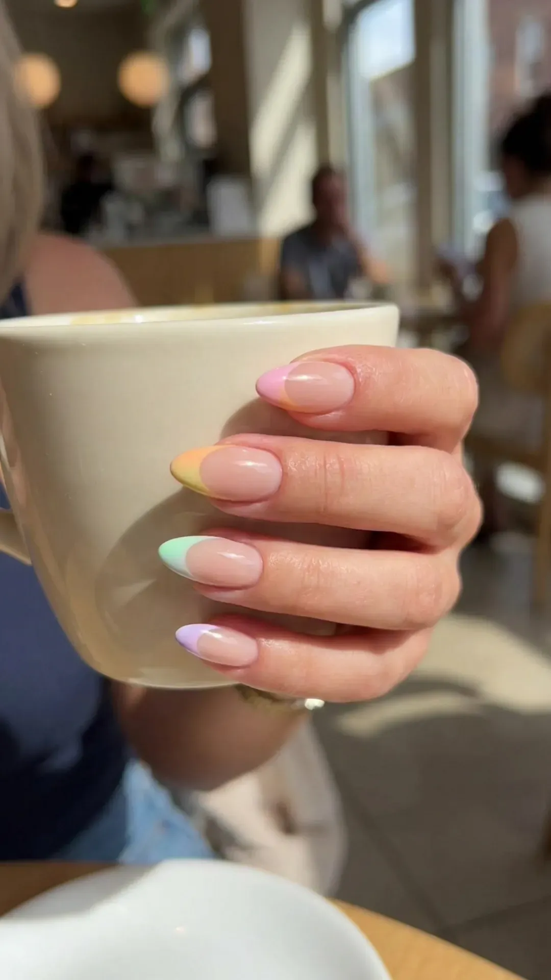 Chic nails with a nude base and pastel rainbow French tips, blending colors for a playful yet refined appearance
