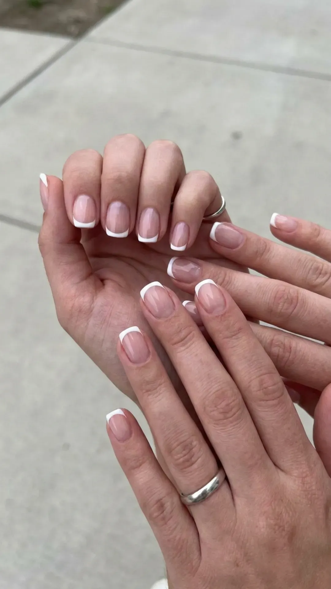 Modern minimalist French nails with a clear base and a striking white tip, embodying a sleek and contemporary style