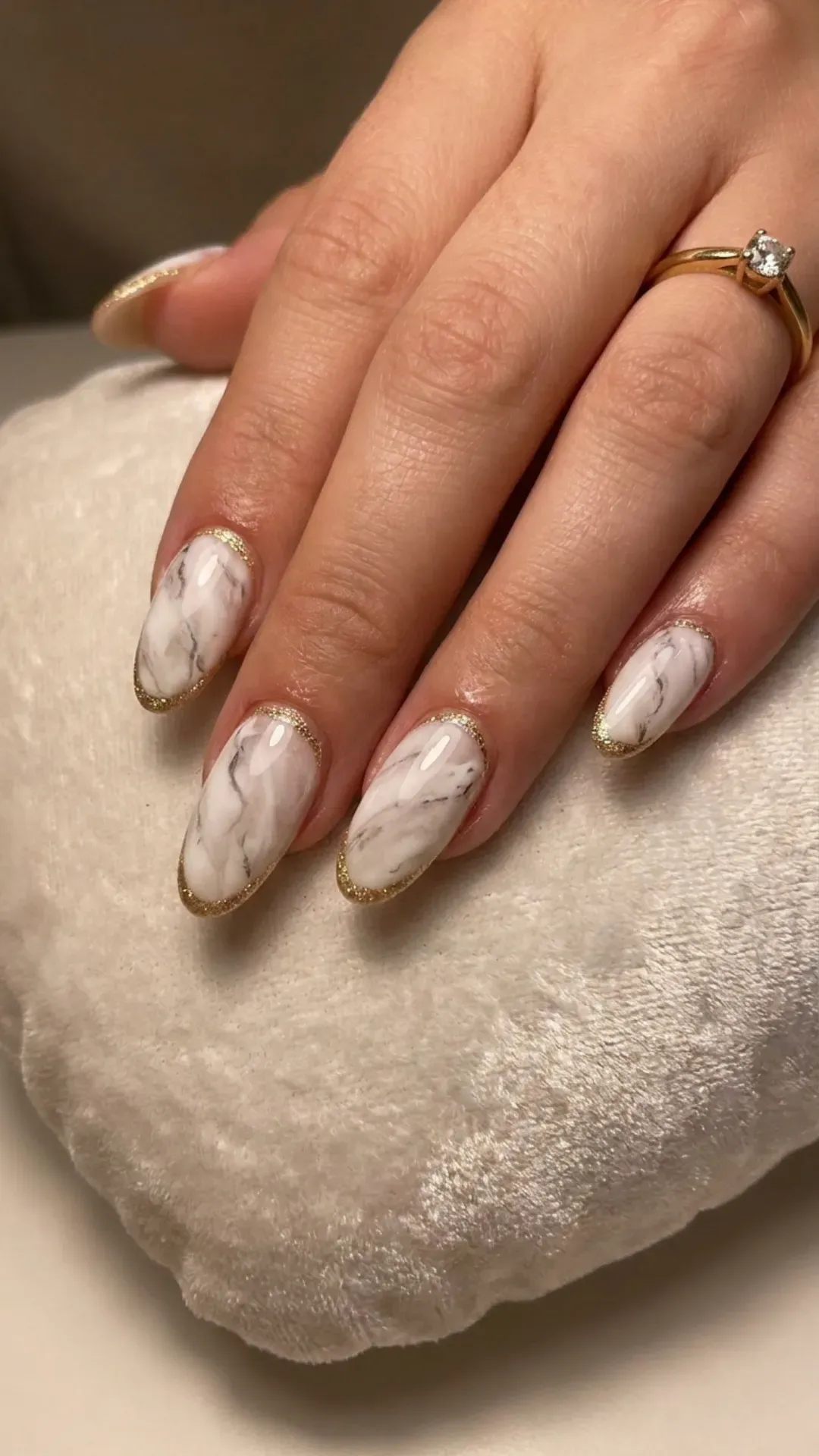 Glamorous white marble nails with gold glitter lining, exuding a chic and opulent nail art look.