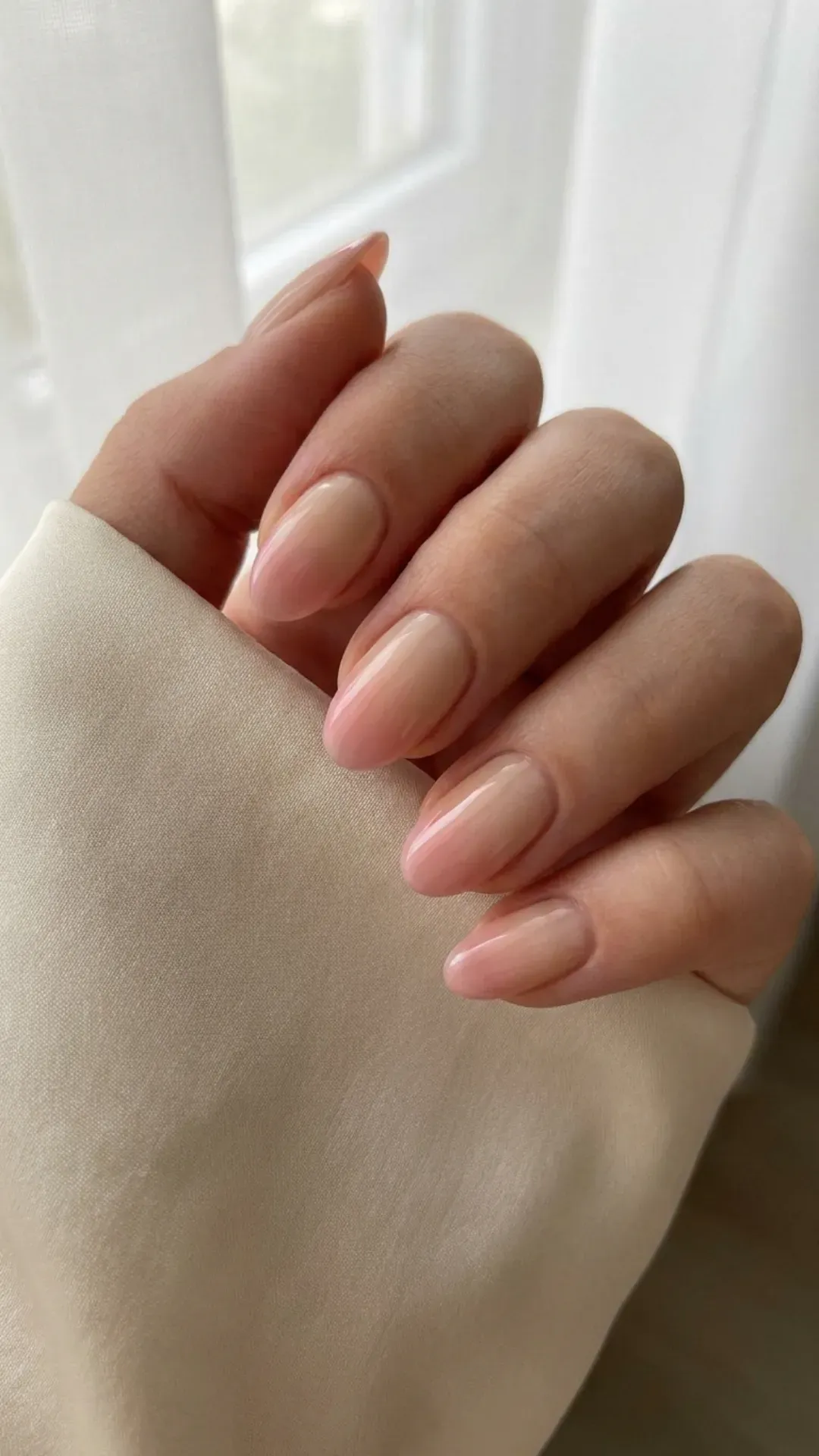 Glossy nails with a natural base and a subtle pink ombre towards the tips, offering a smooth color transition for an elegant effect