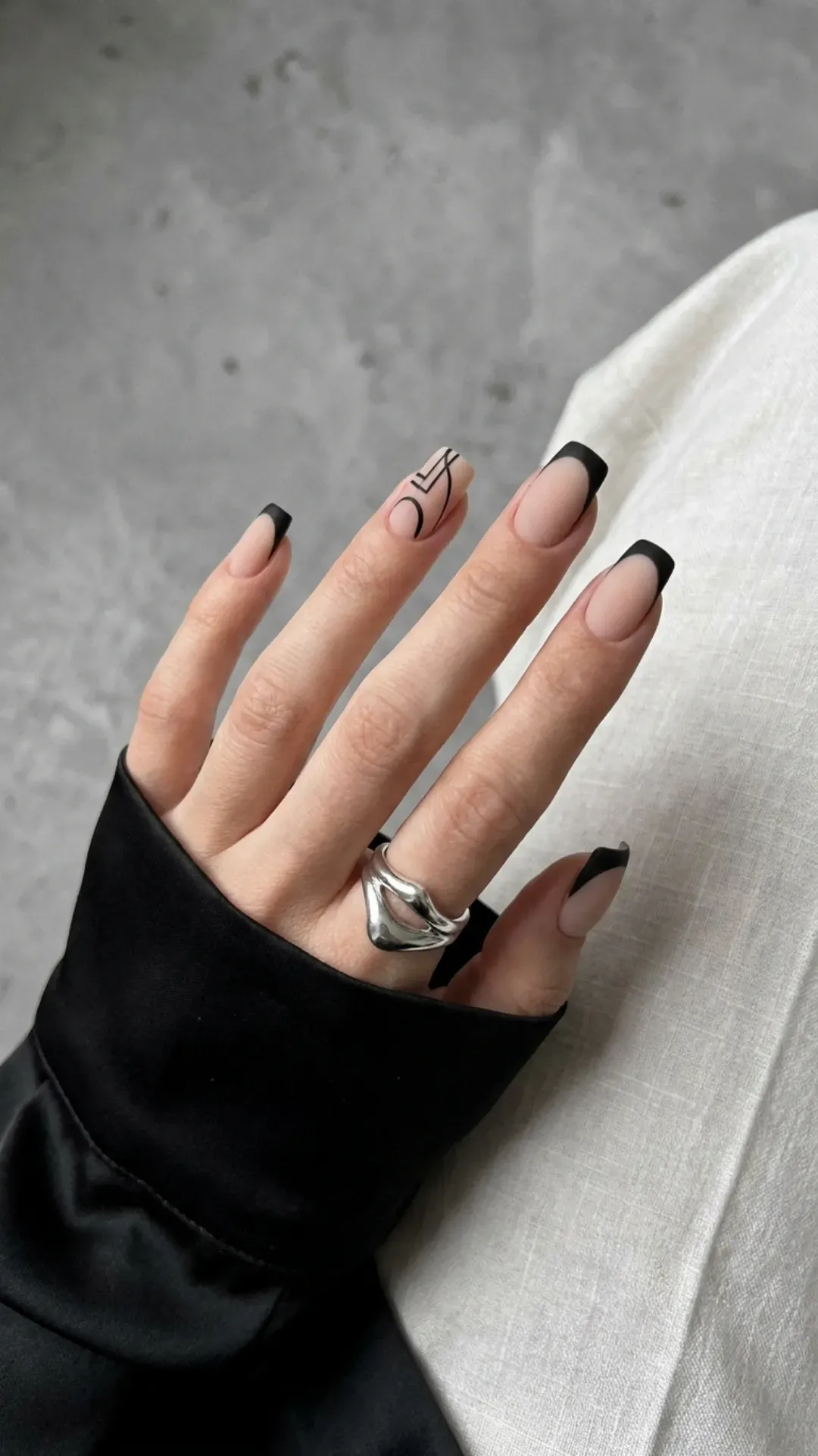 Fashion-forward French manicure with a matte nude base and a bold black edge, showcasing a sophisticated monochrome style