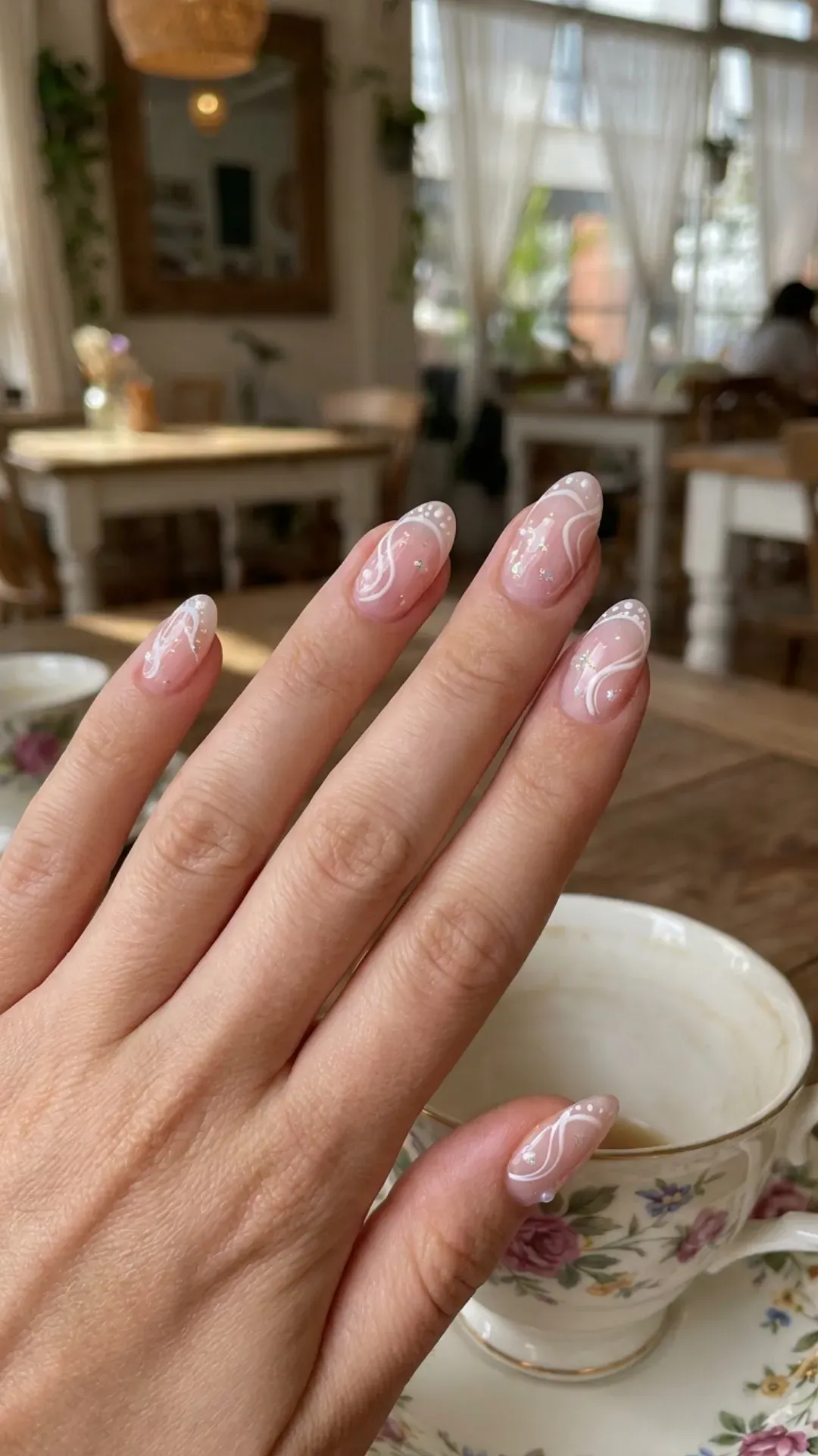 Creative French manicure with a sheer base and white artistic swirls on the tips, adding a whimsical touch to the classic design.