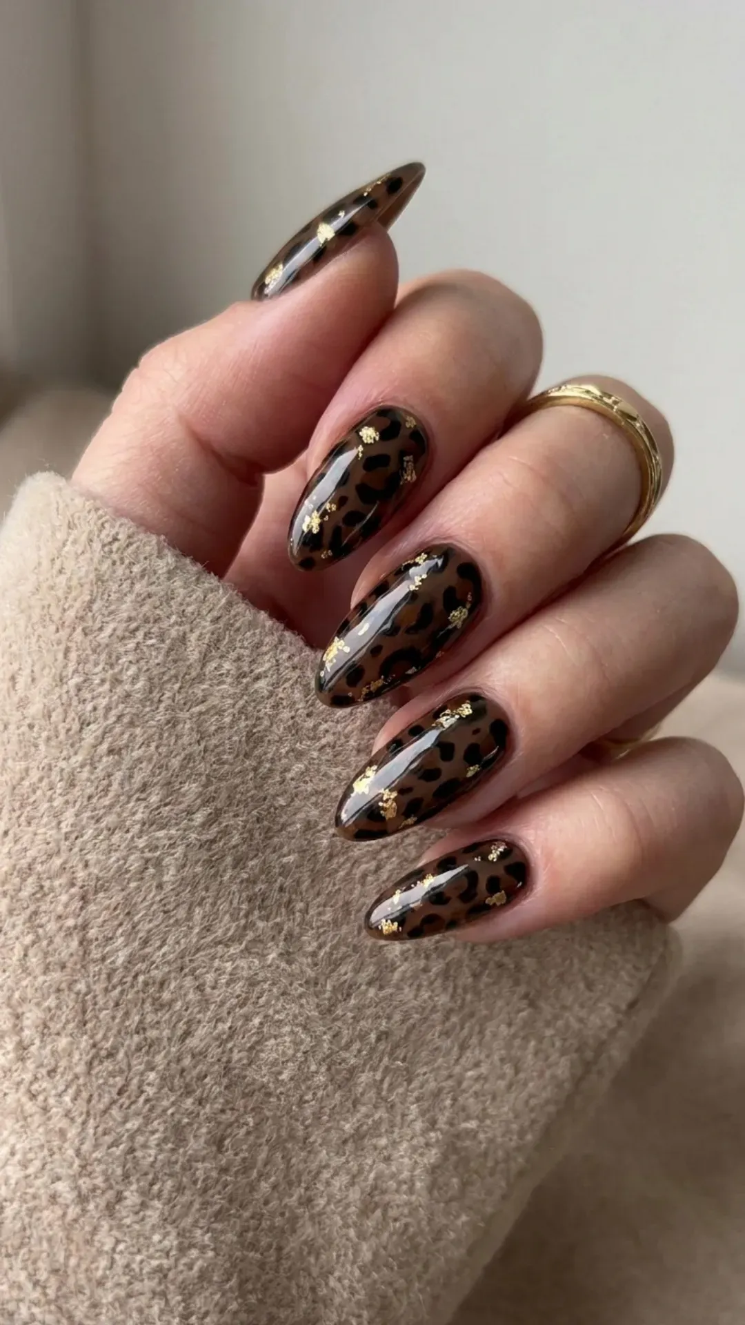 Leopard Print Nails with Gold Accents - Almond-shaped nails with glossy brown and black leopard spots and gold flecks