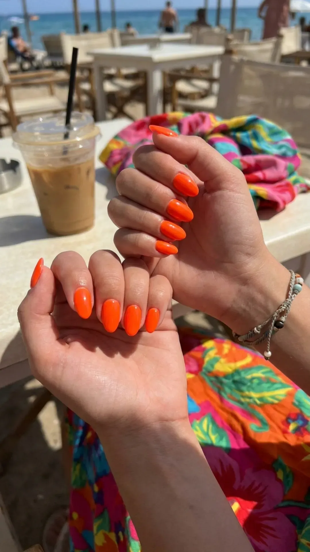 Close-up of hands with neon orange nail polish, showcasing the vibrant and bold color perfect for summer 2026 trends.
