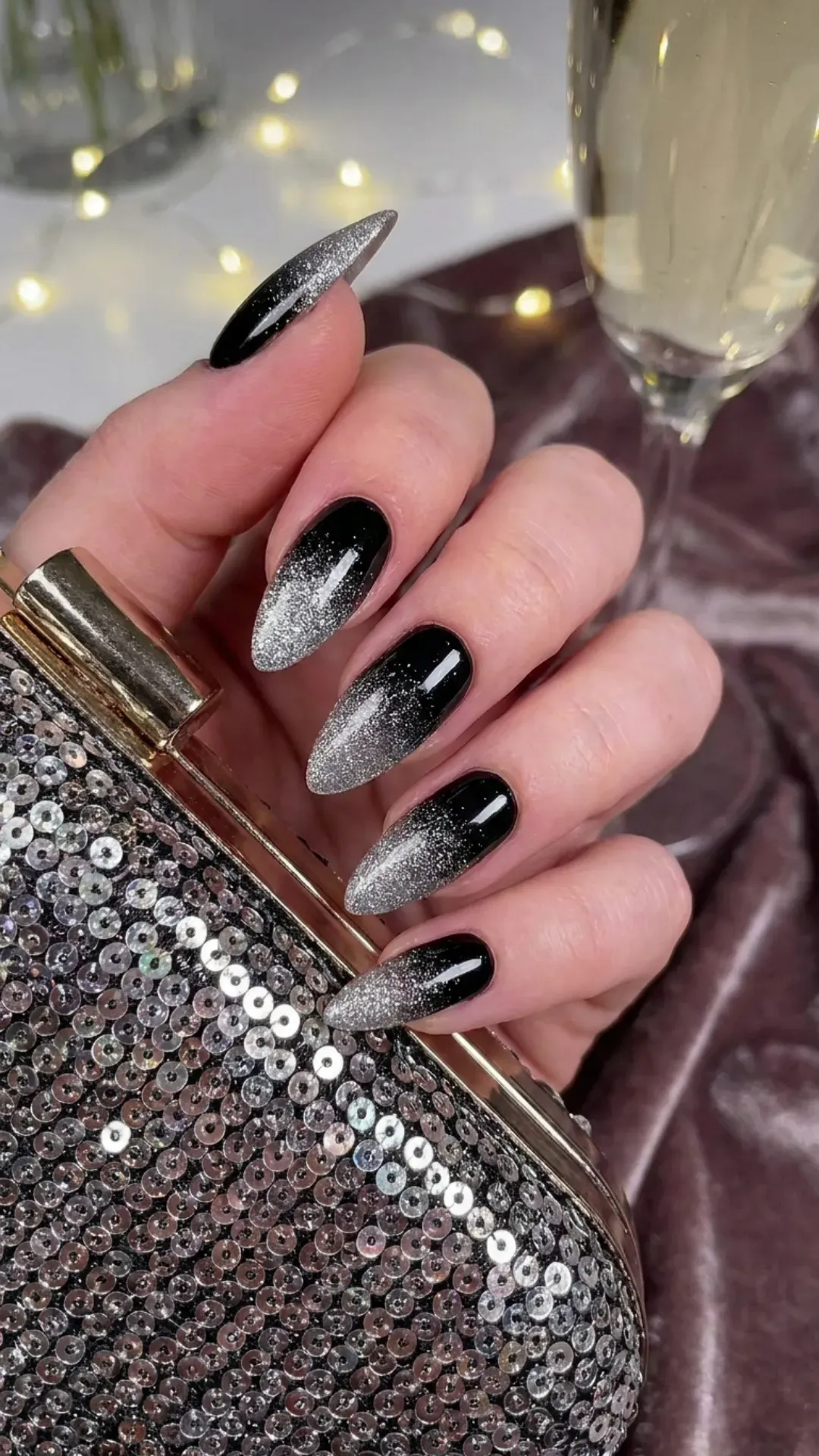 Chic ombre nail design featuring a black base with a sparkling transition to silver glitter towards the nail tips, perfect for a glamorous evening event.