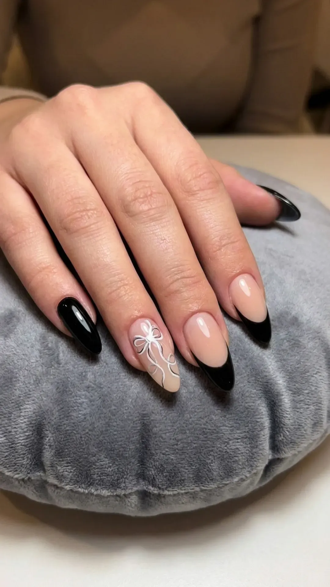 Classic black nails alternating between solid color and French tips, enhanced with delicate hand-drawn ribbon designs.