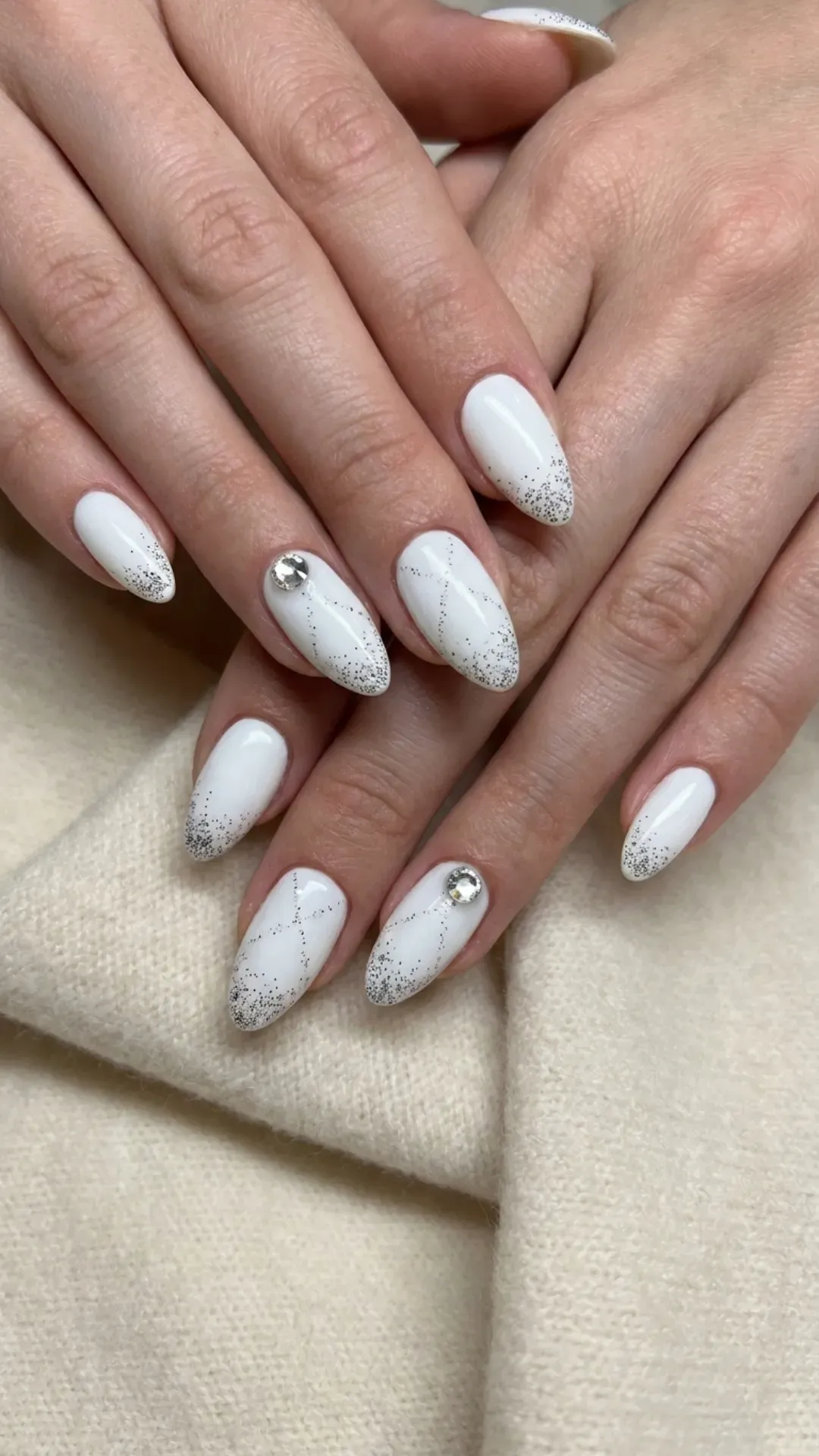 Sophisticated nail art with a white base and black glitter accents, finished with a single rhinestone on each ring finger for a touch of elegance.