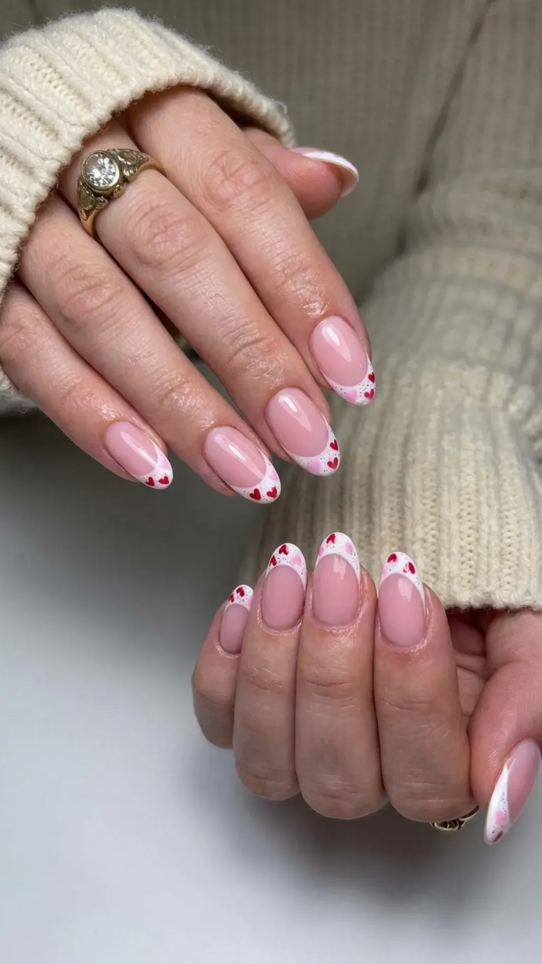 Charming French tip nails with a twist, featuring pink bases and white tips adorned with small, delicate heart designs