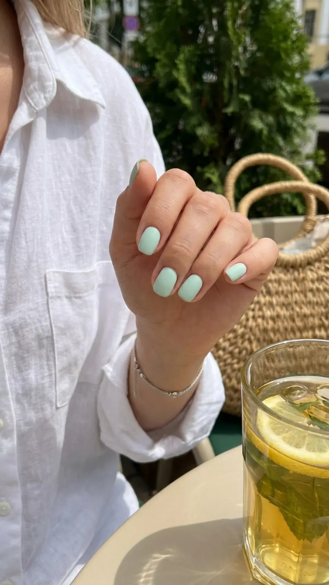 Hand with mint green short nails, highlighting a fresh and cool color trend for summer 2026, perfect for a subtle look.