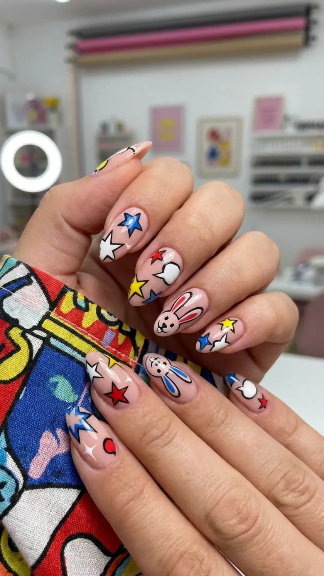 Soft nude pink nails showcasing pop art-inspired patterns with stars and cute rabbit motifs, presenting a playful twist on a chic nail trend.