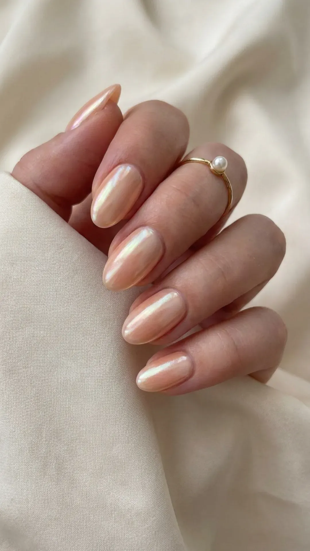 Oval nails with upgraded glazed donut finish — soft peach base with pearlescent chrome shimmer, luminous and multidimensional — 2026