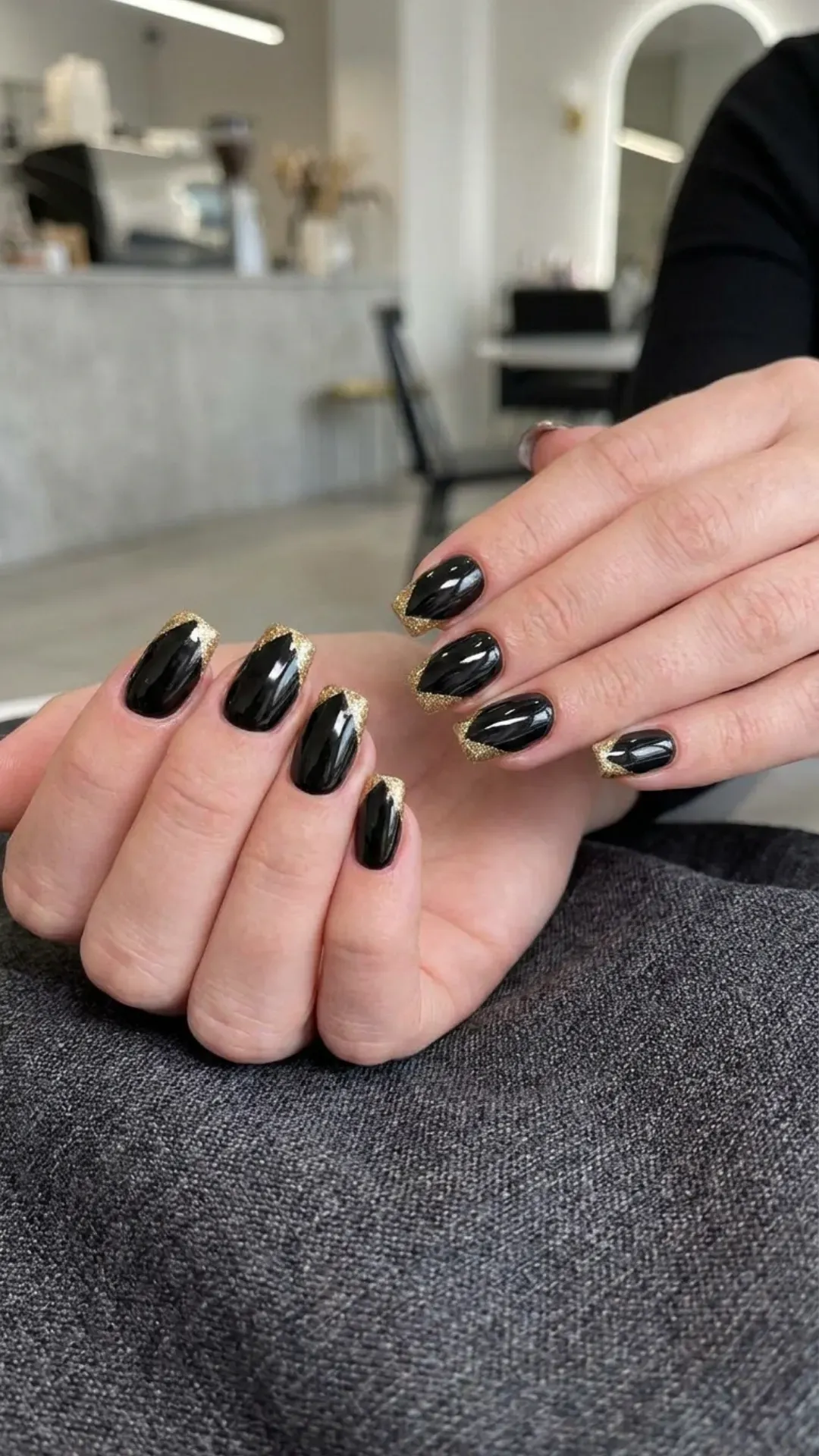 A modern twist on the classic French tip with black nails featuring golden glitter tips, providing a chic and trendy look suitable for any occasion.
