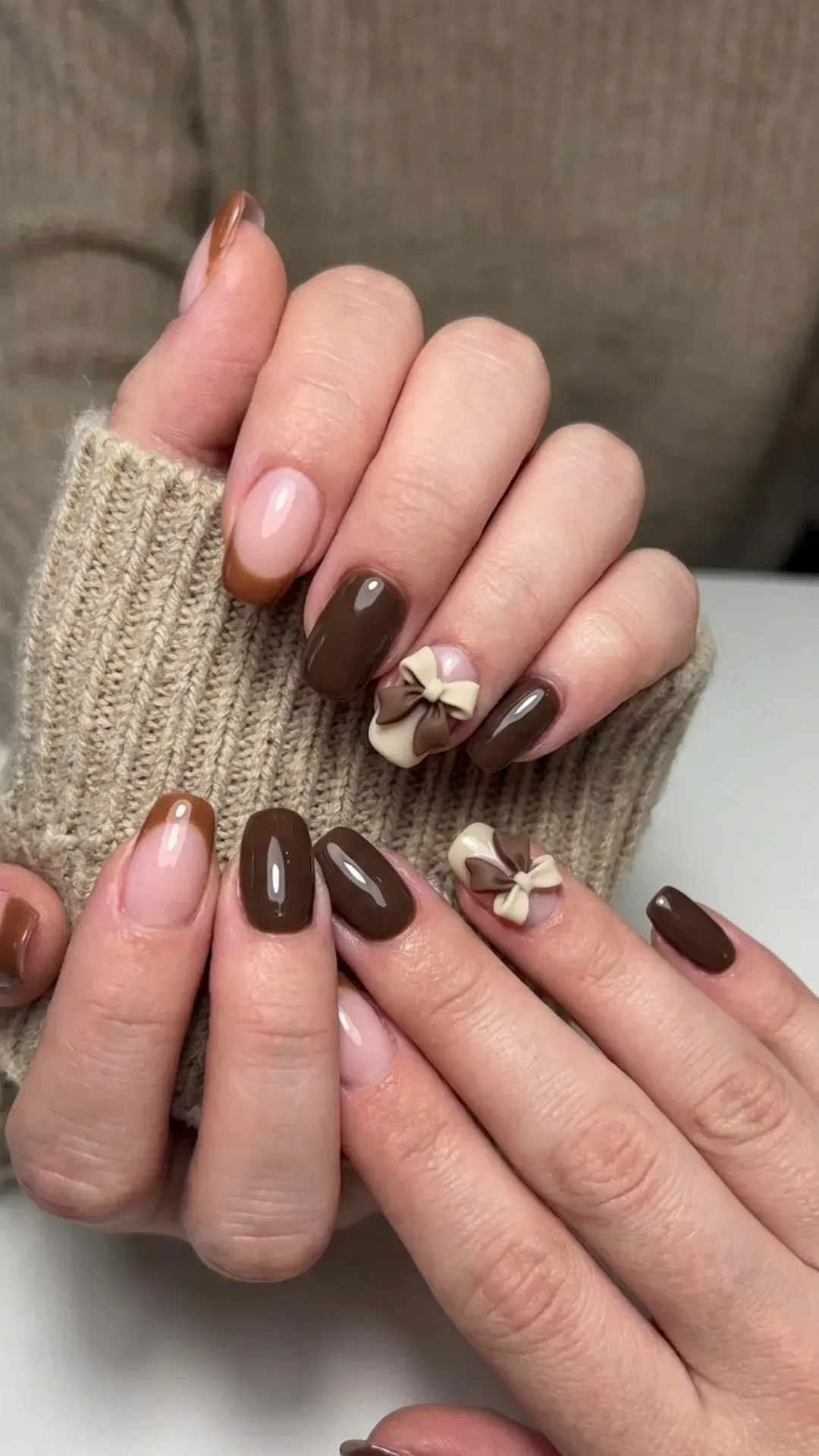 Brown French tips paired with solid brown nails and accented with layered 3D bows for a warm and stylish look.